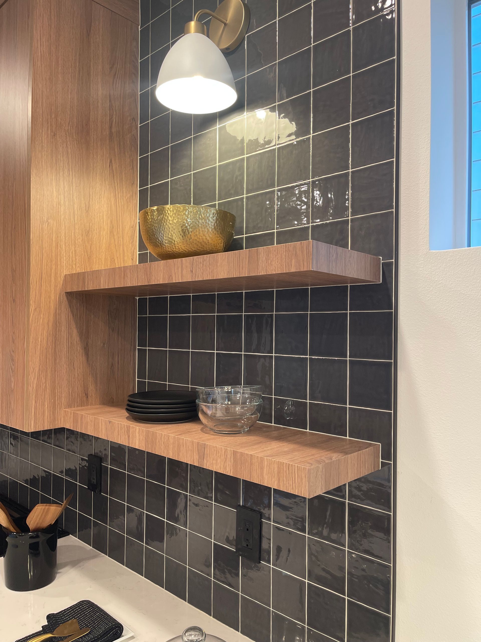 Kitchen corner with dark tile backsplash, floating wood shelves, and a decorative gold bow pro-techwoodwoorking.