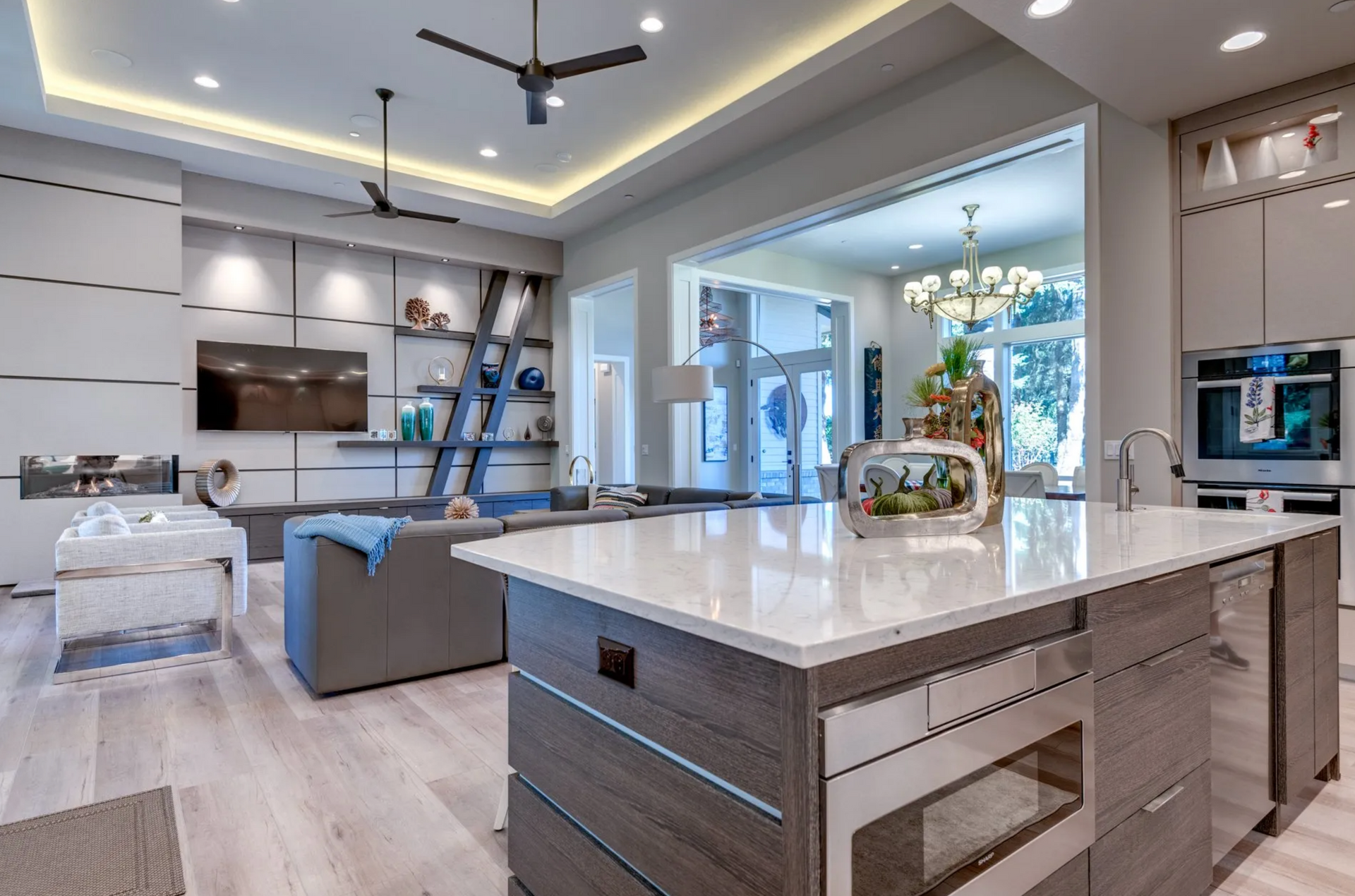 Modern open-concept living space with kitchen island, living room with TV, and dining room visible.