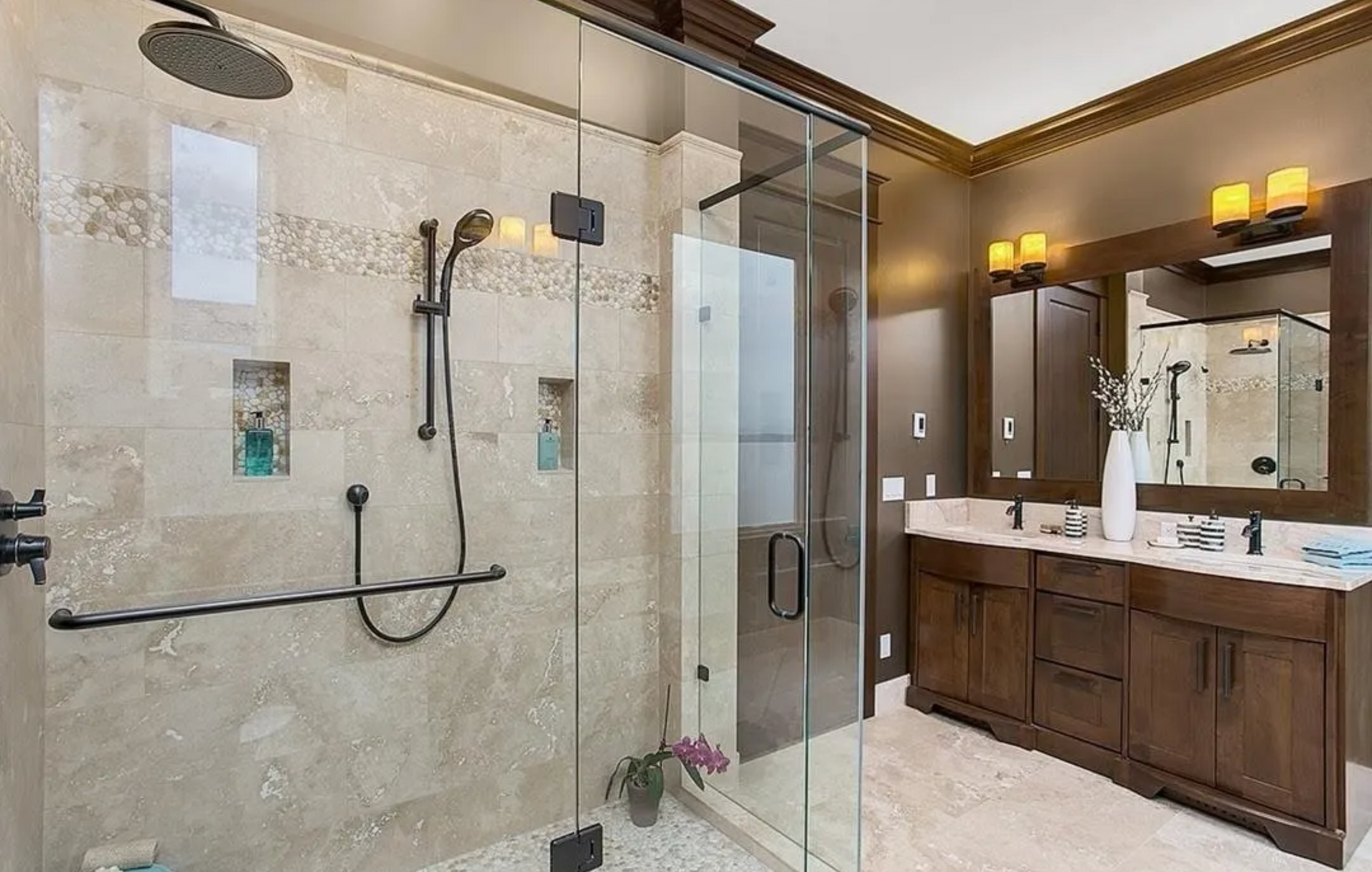 Bathroom with glass shower, double vanity, beige tile, and dark wood cabinets.