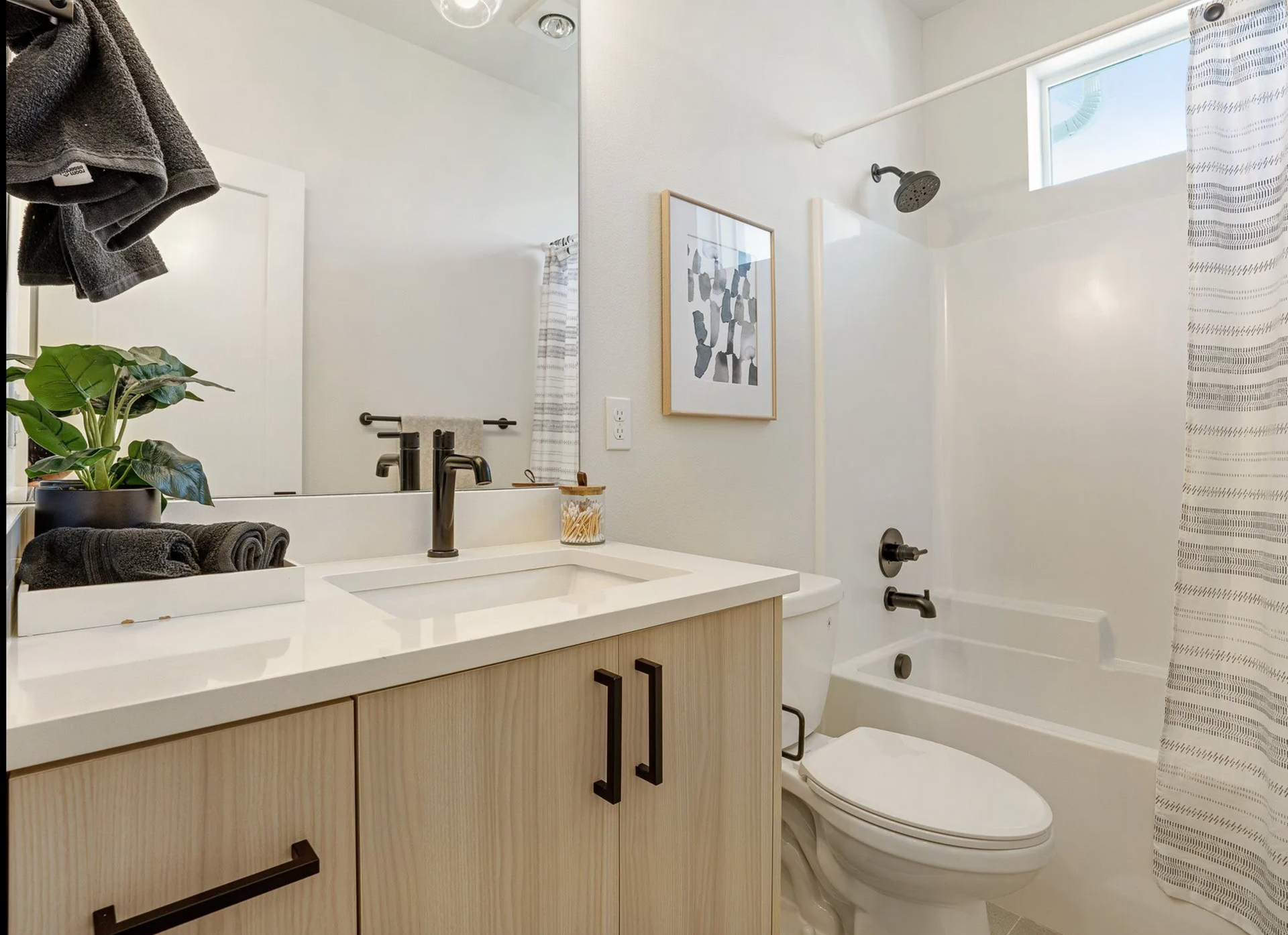 Modern bathroom with light wood vanity, white sink, and shower/tub combo.