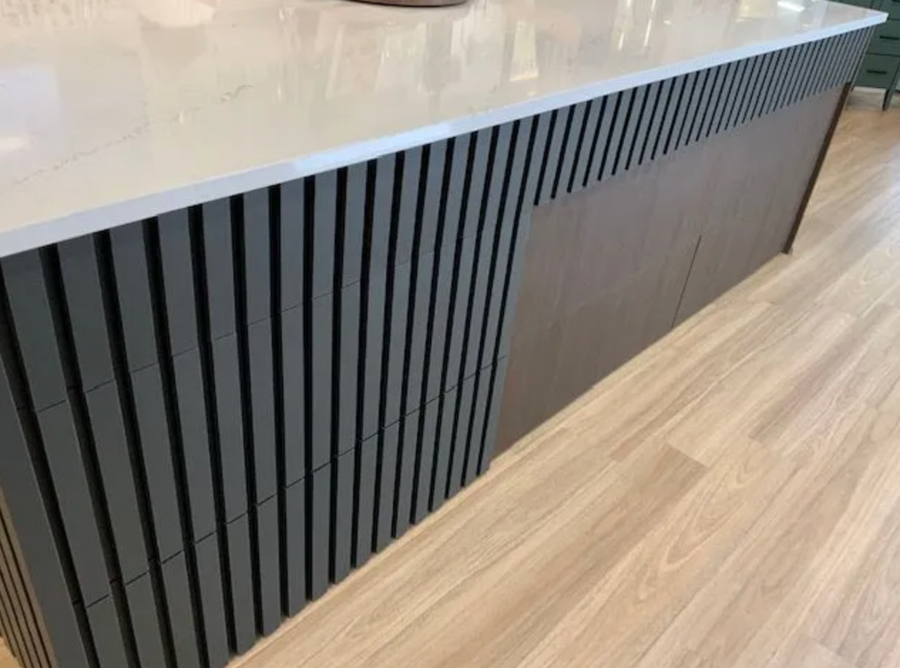 Dark vertical slat front counter on light wood flooring in commercial space