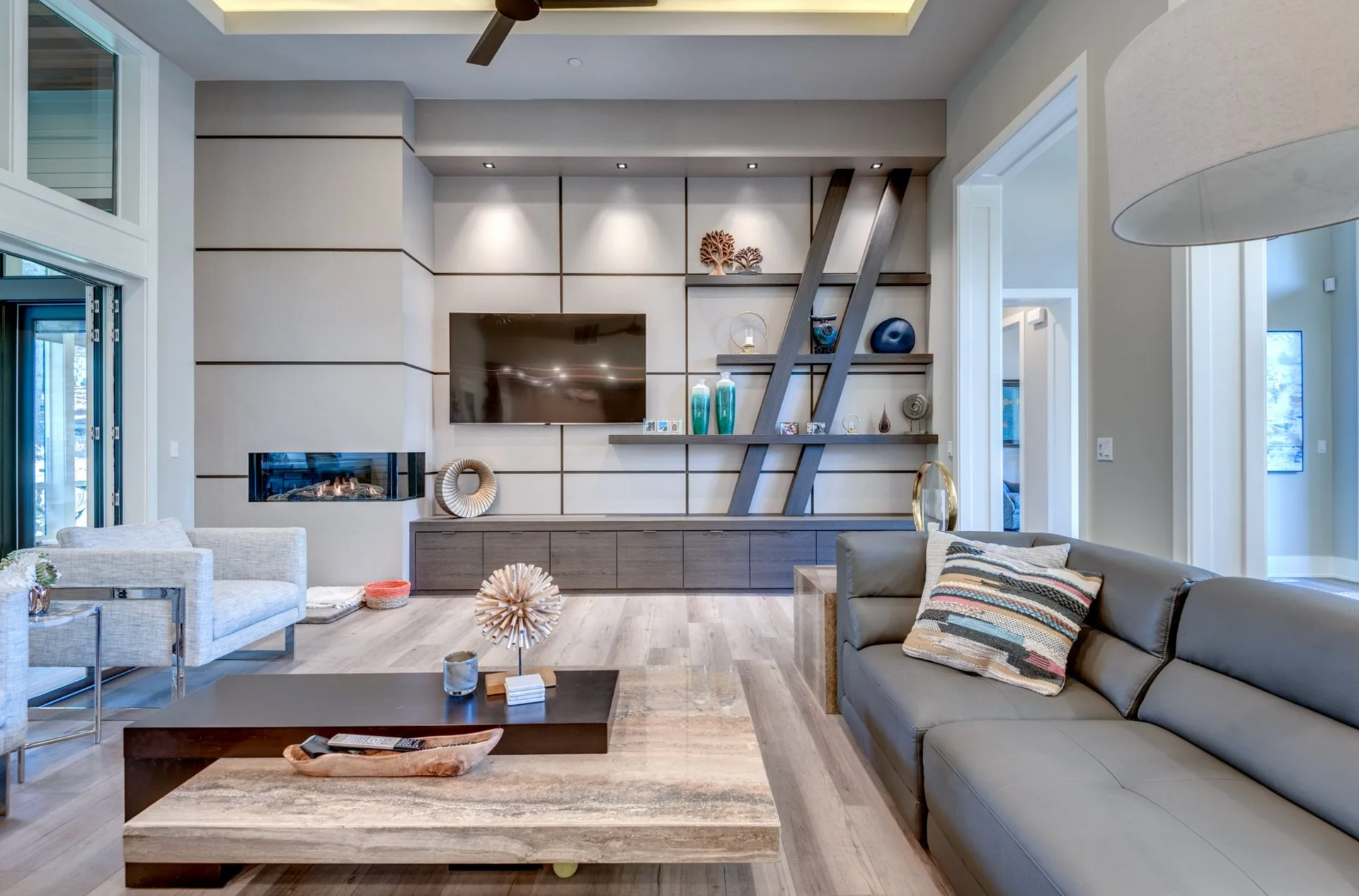 Modern living room with gray sectional, fireplace, and built-in media center.