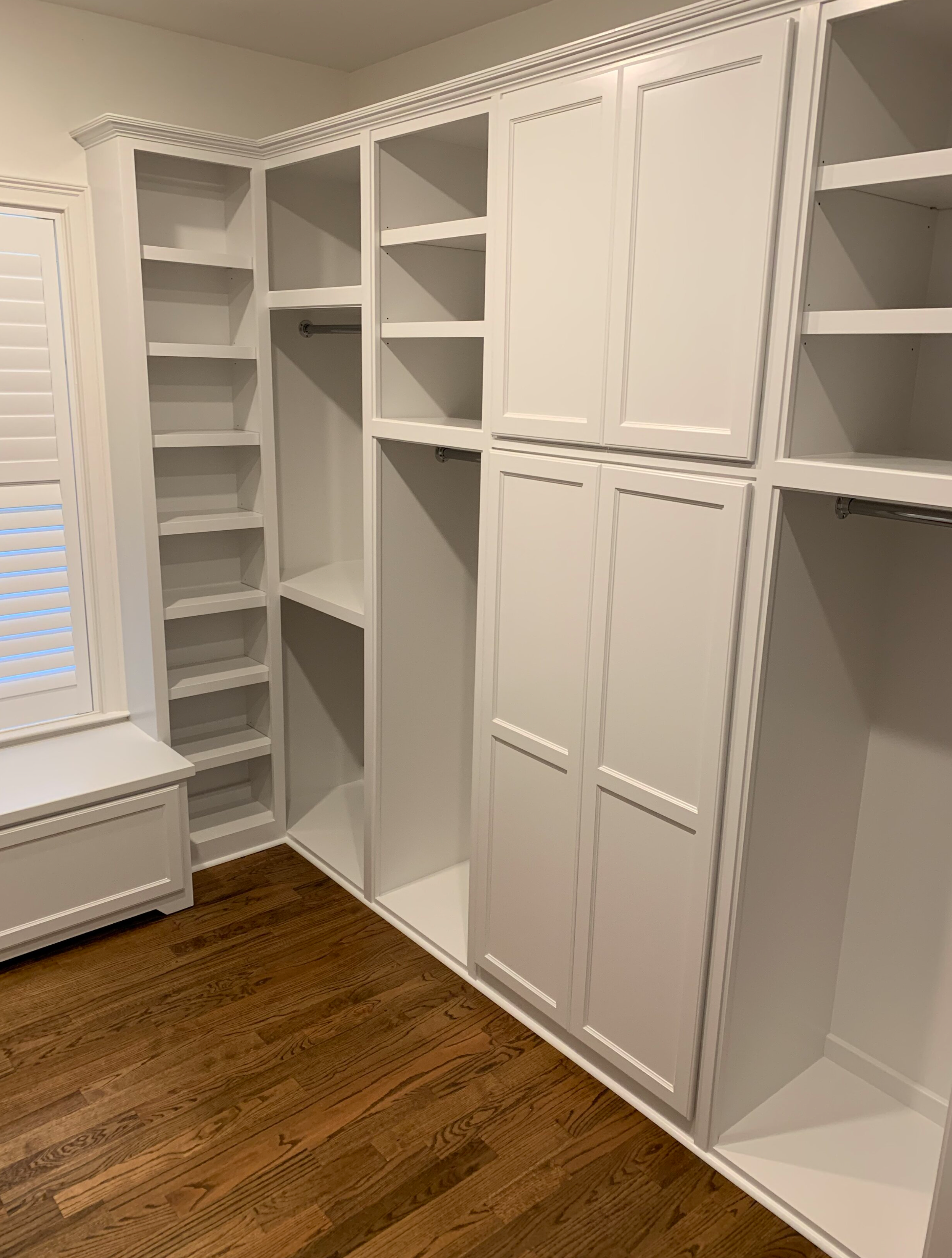 Tall white closet cabinets with built-in shelves and overhead storage in Portland by Pro-Tech Woodworking
