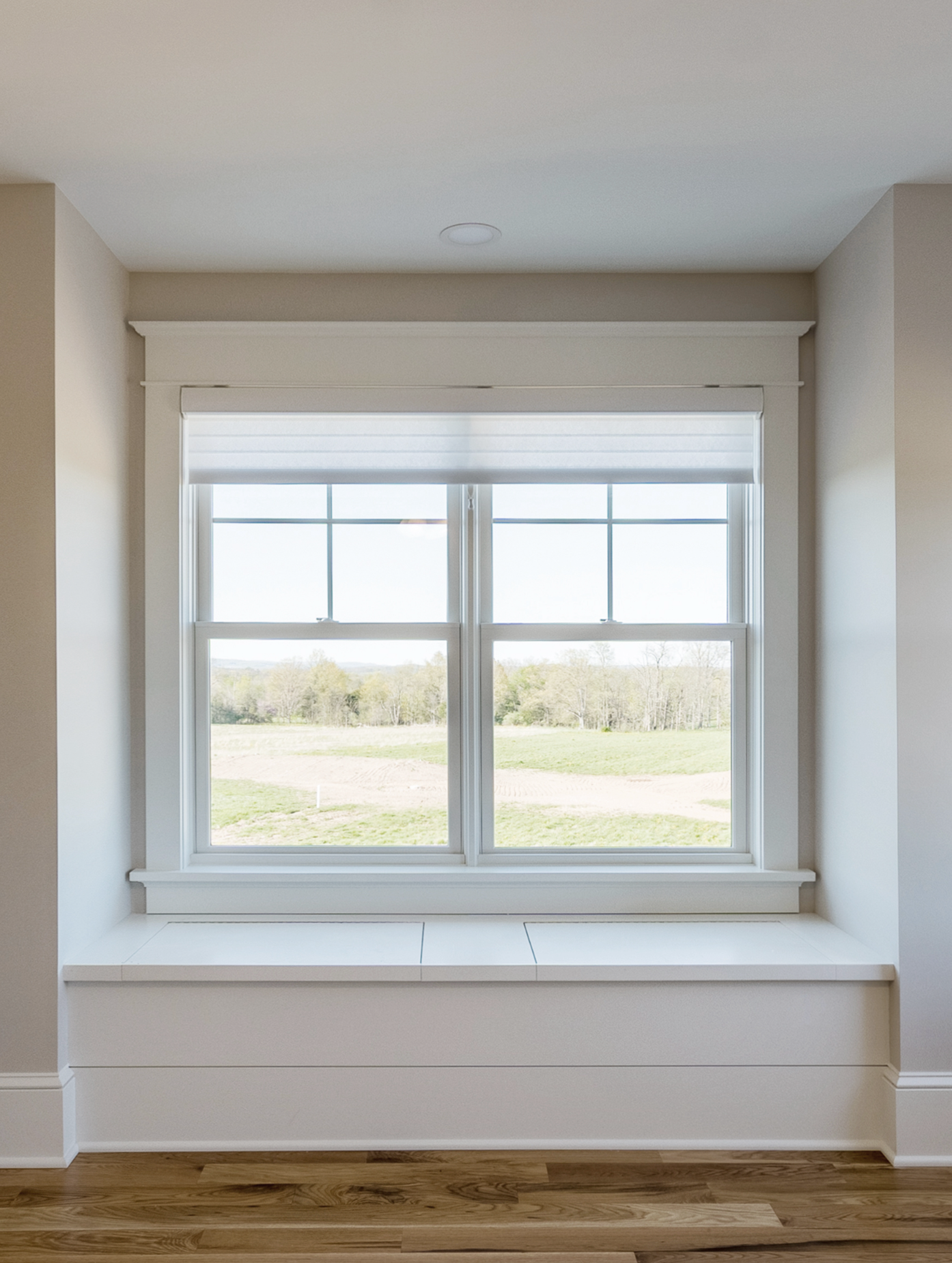 Wide window with built-in sill and white trim, overlooking open landscape in Portland by Pro-Tech Woodworking