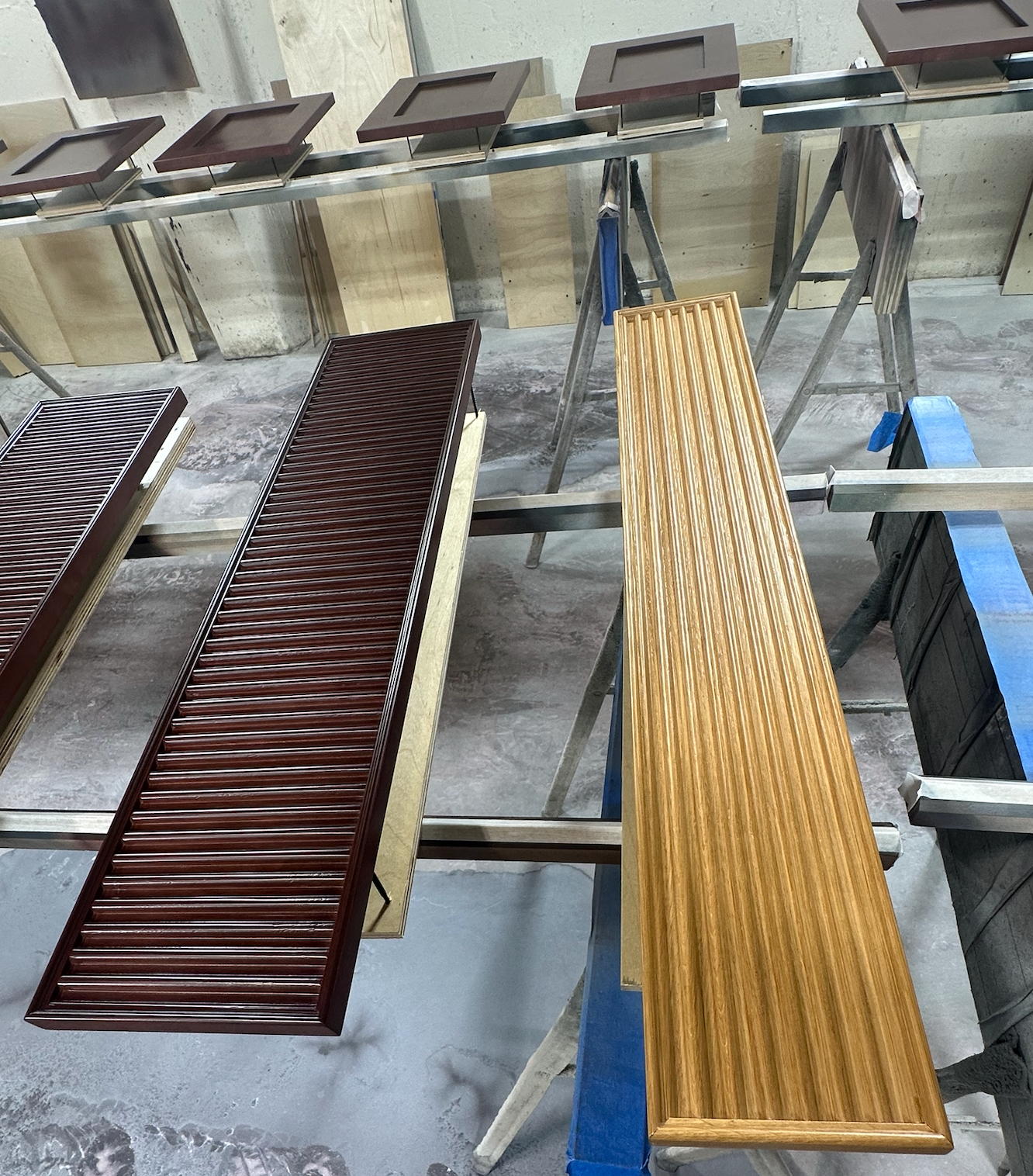 Painted cabinet doors drying on racks in a workshop.