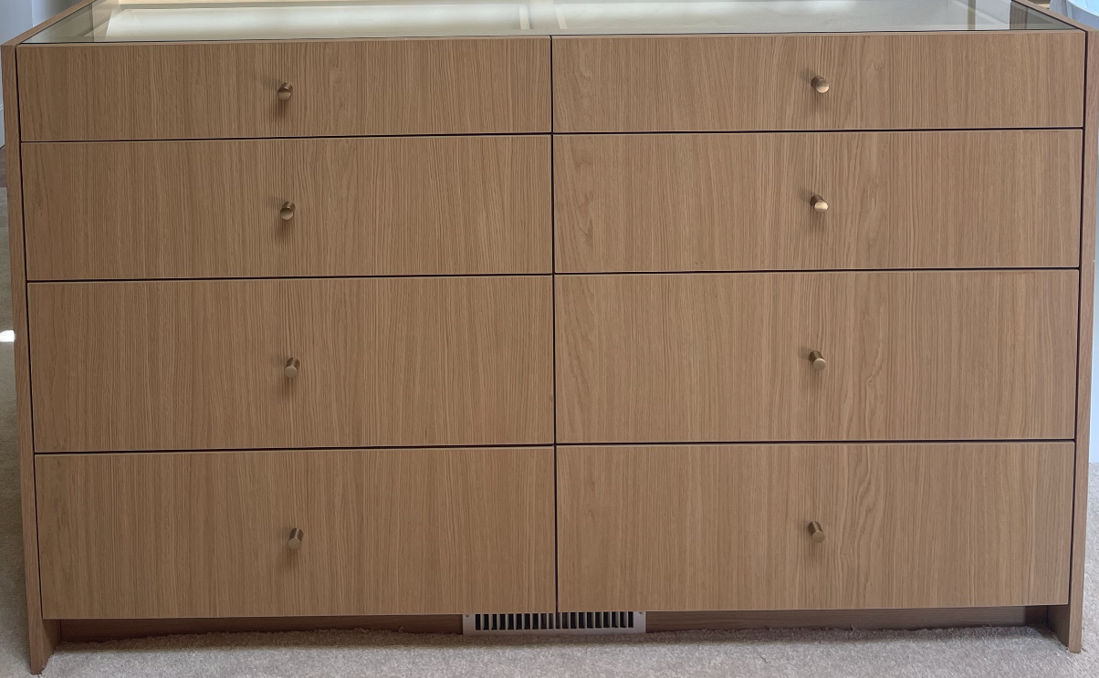 Wooden dresser with eight drawers, light brown vertical grain, gold knobs.