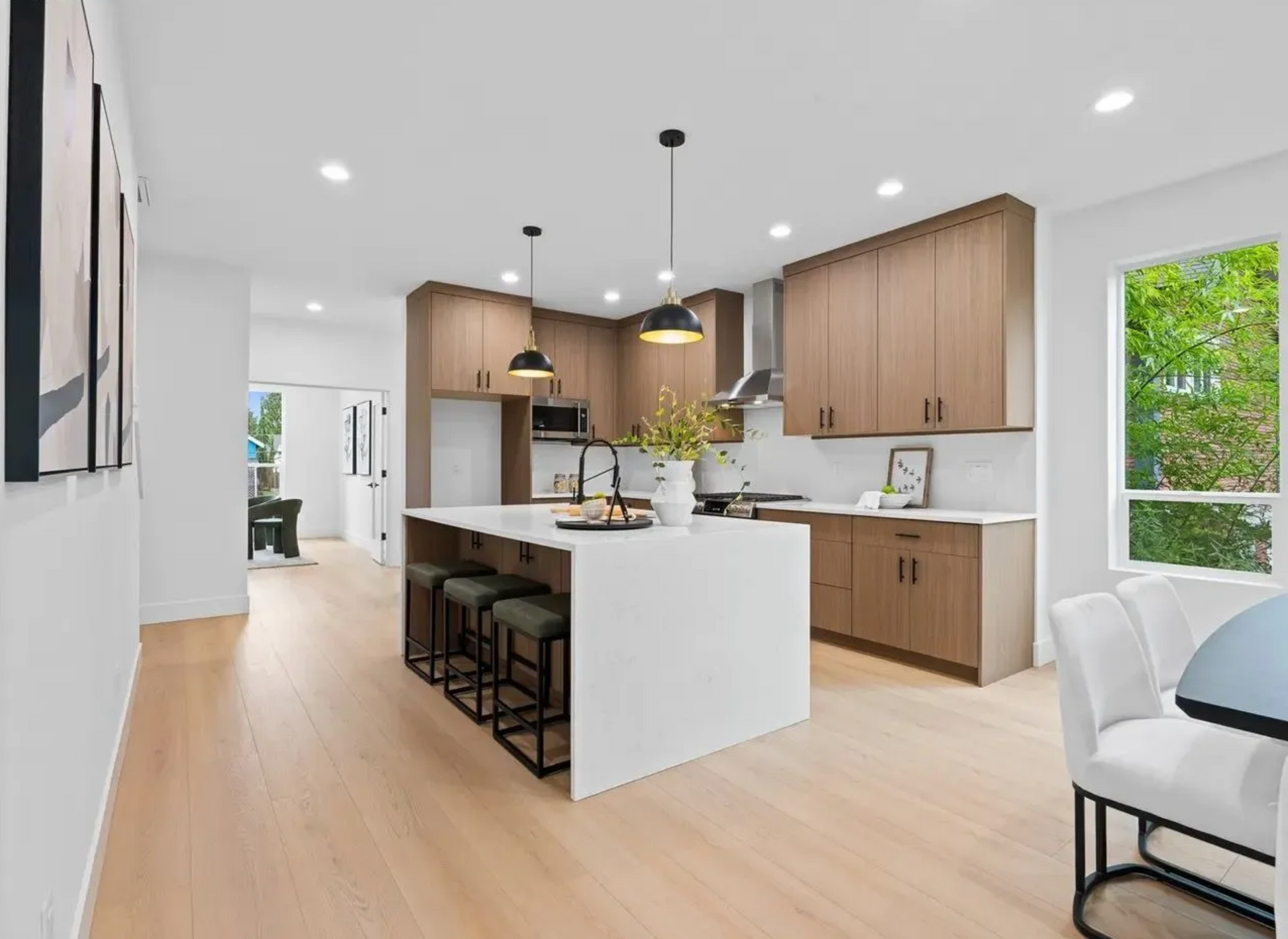 Modern kitchen with light wood cabinets, white island with stools, and light wood flooring.