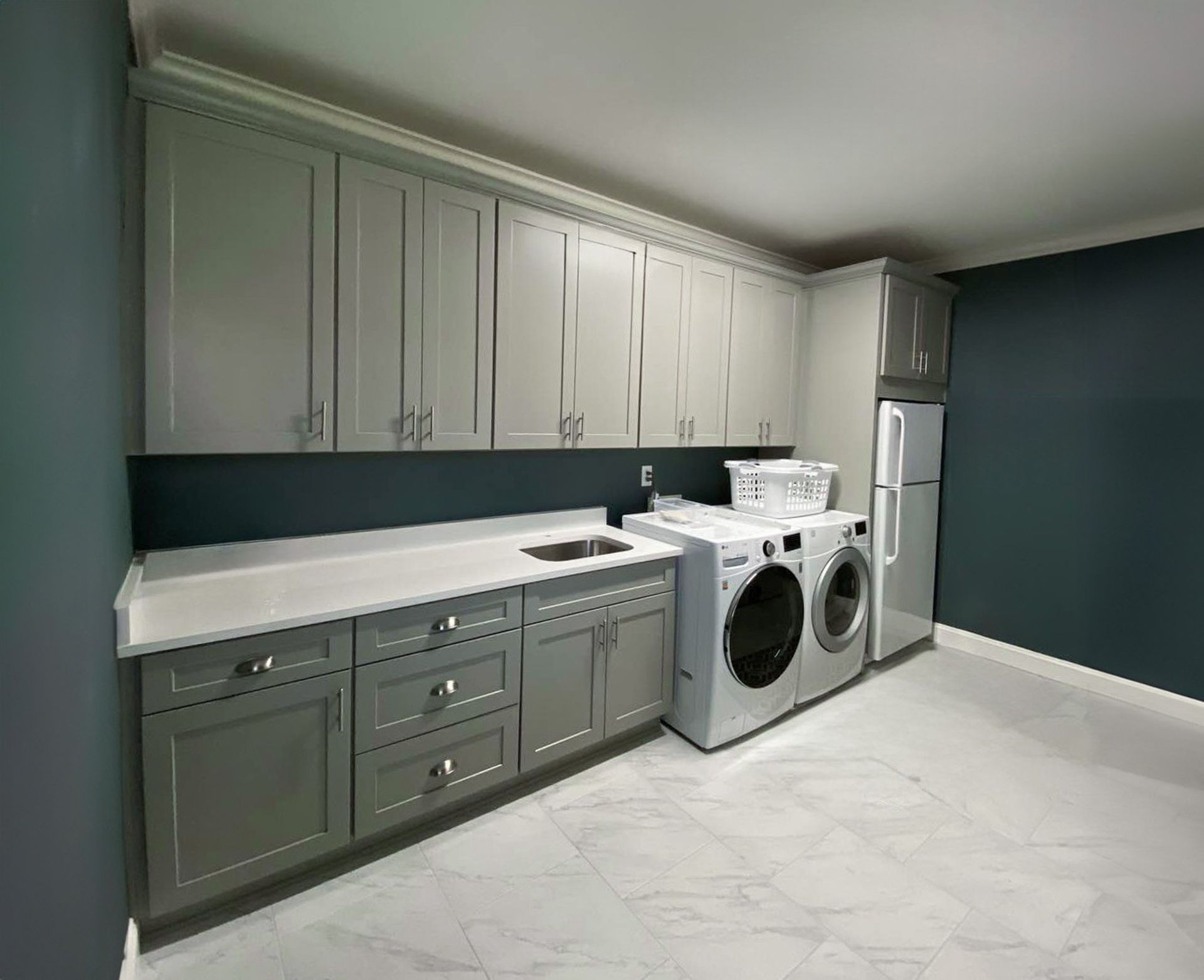 Custom gray laundry room with upper and lower cabinets, washer and dryer