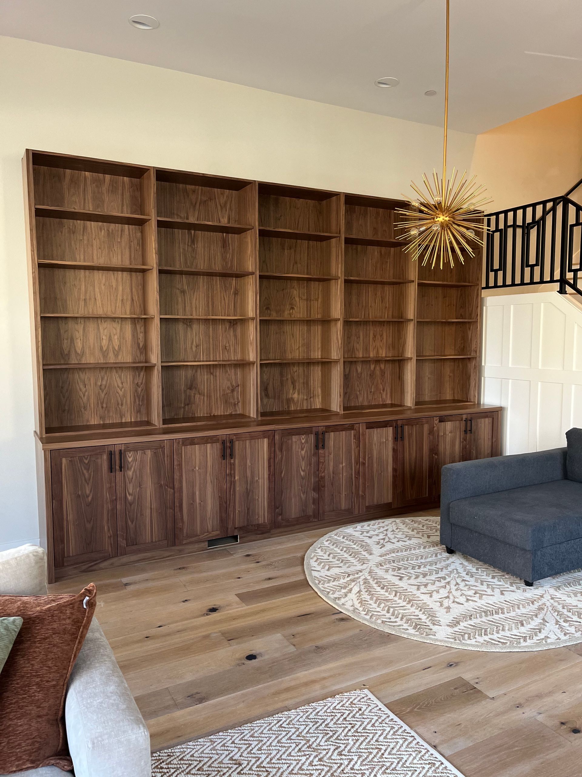 Built-in wooden bookshelves with closed cabinets below against a light wall, modern living room.