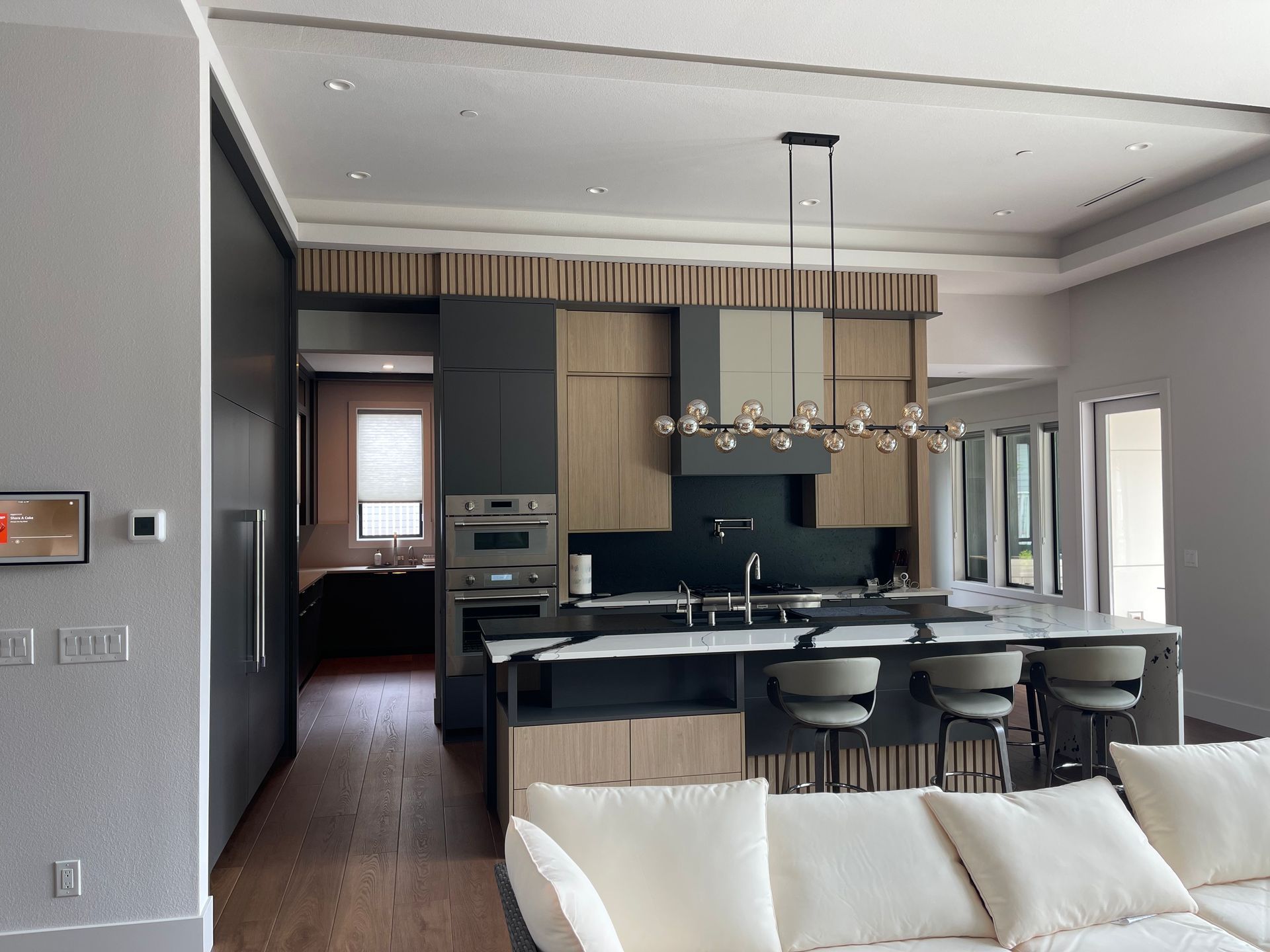 Modern kitchen with island, light wood cabinets, and dark gray accents.