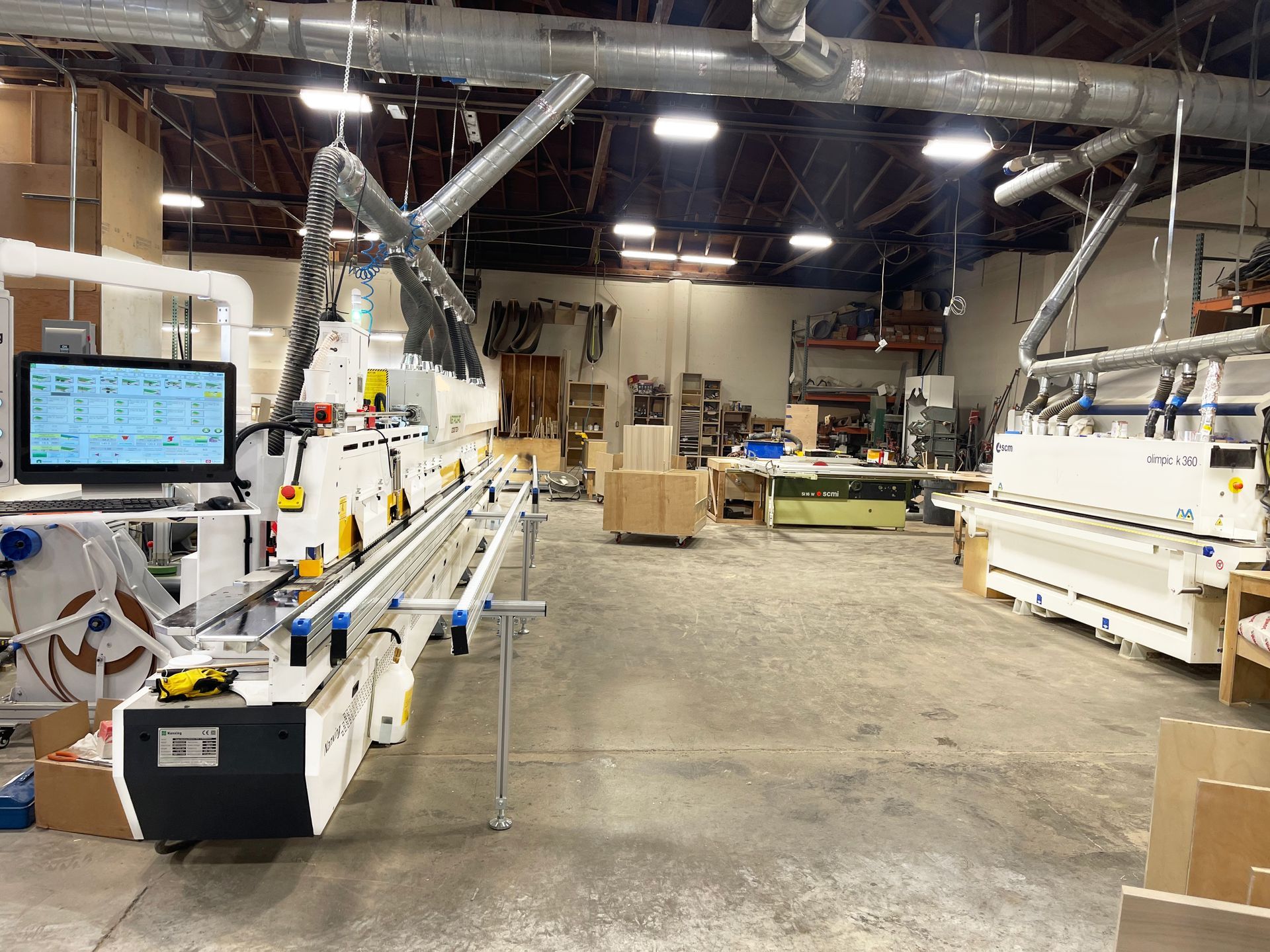Modern woodworking production floor with professional edgebanding machine and dust extraction system