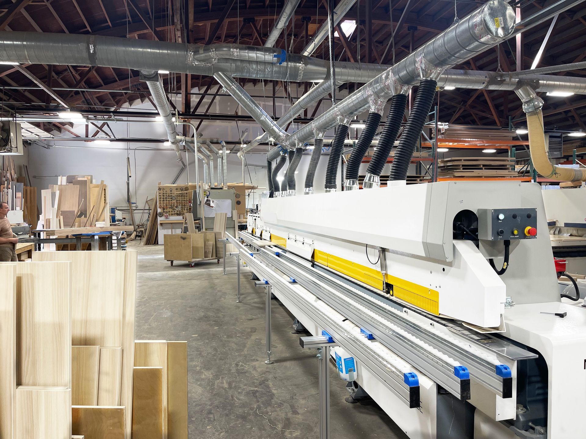 Factory floor with large woodworking machine processing lumber.