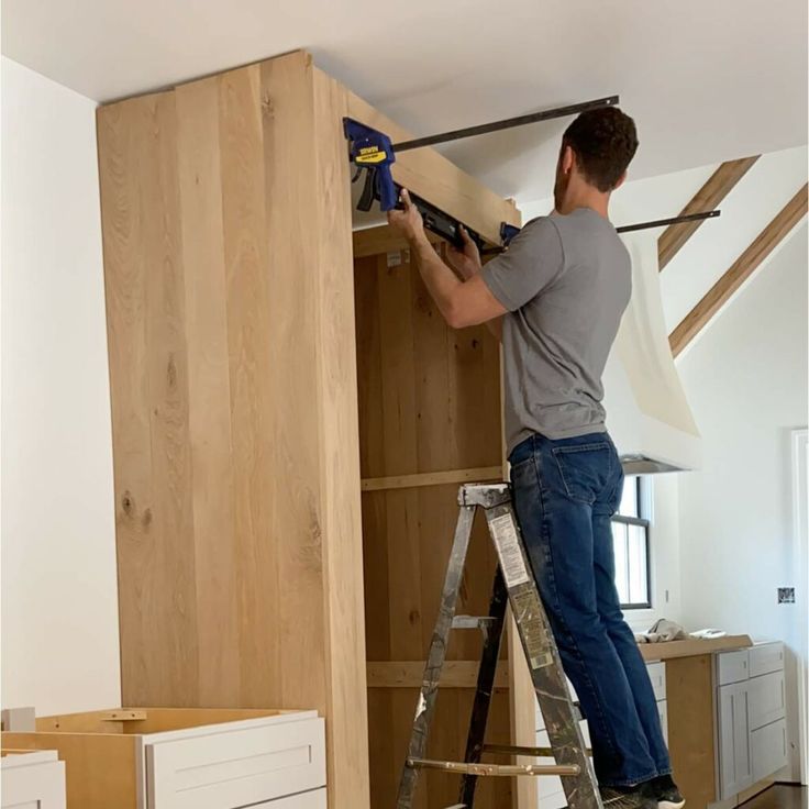 Cabinet installer in Portland mounting large vertical panel on-site with tools
