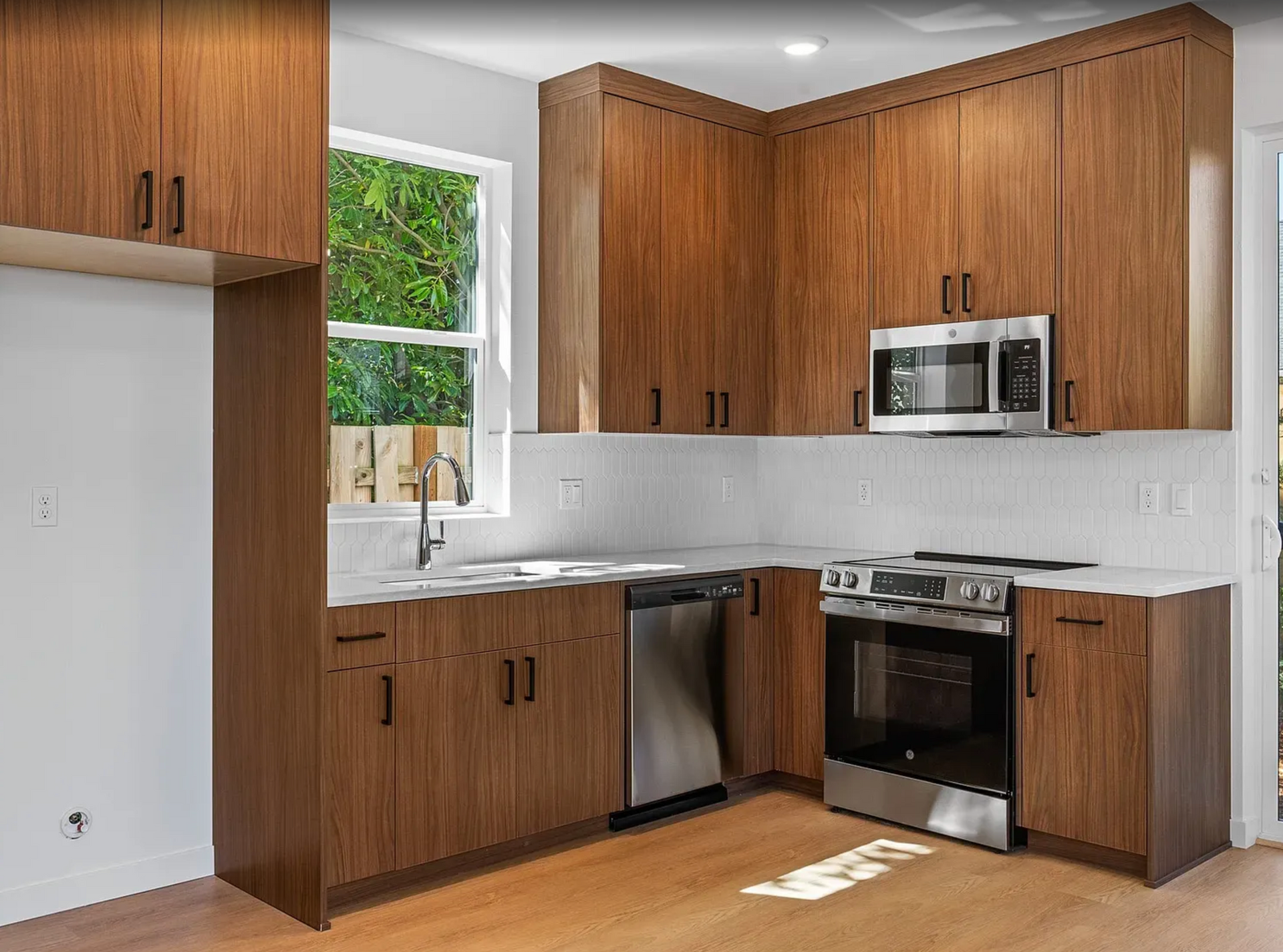 Modern kitchen with brown cabinets, stainless steel appliances, and white countertops.