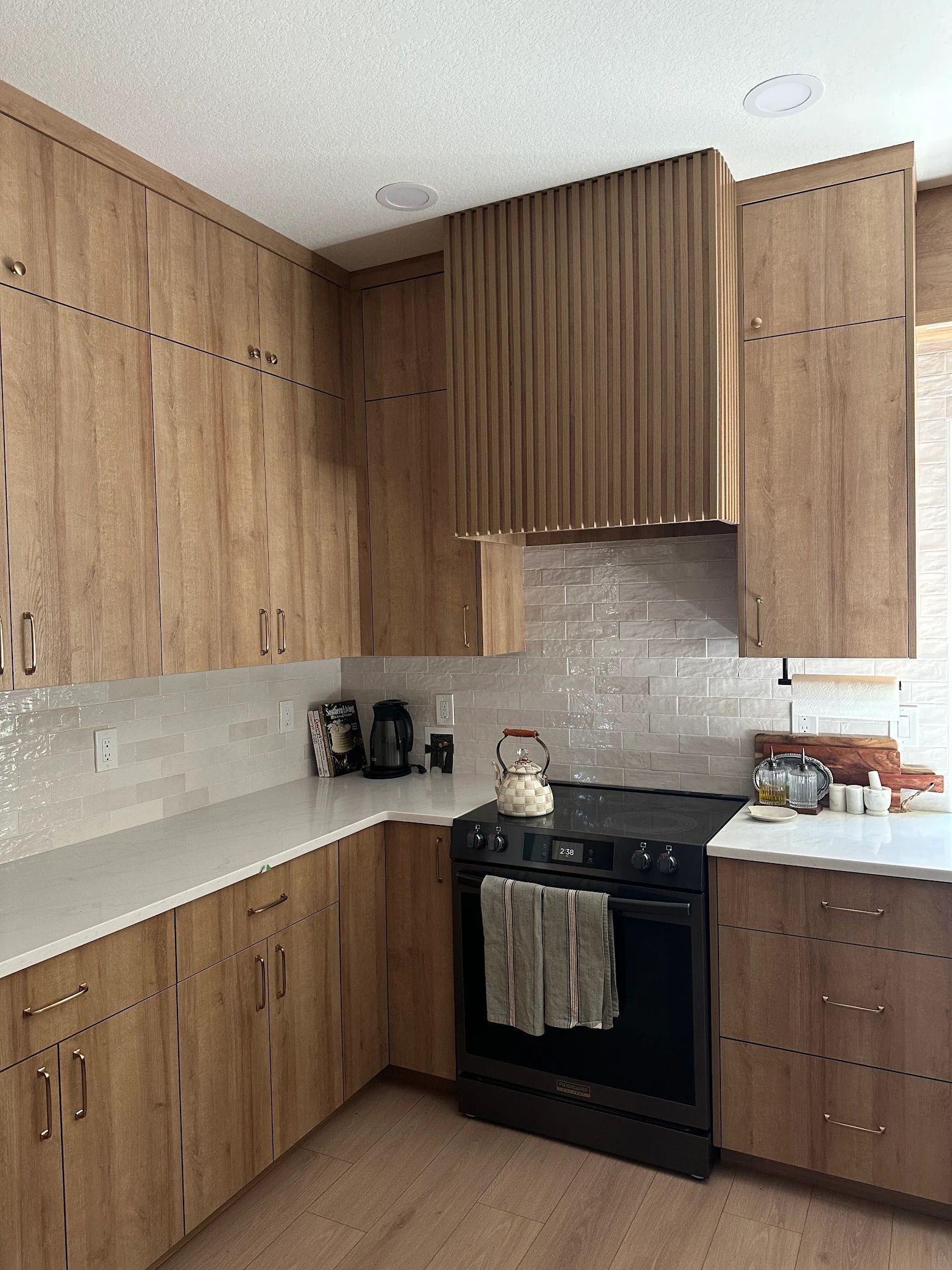 Wooden kitchen cabinets with white countertops and a black stove.