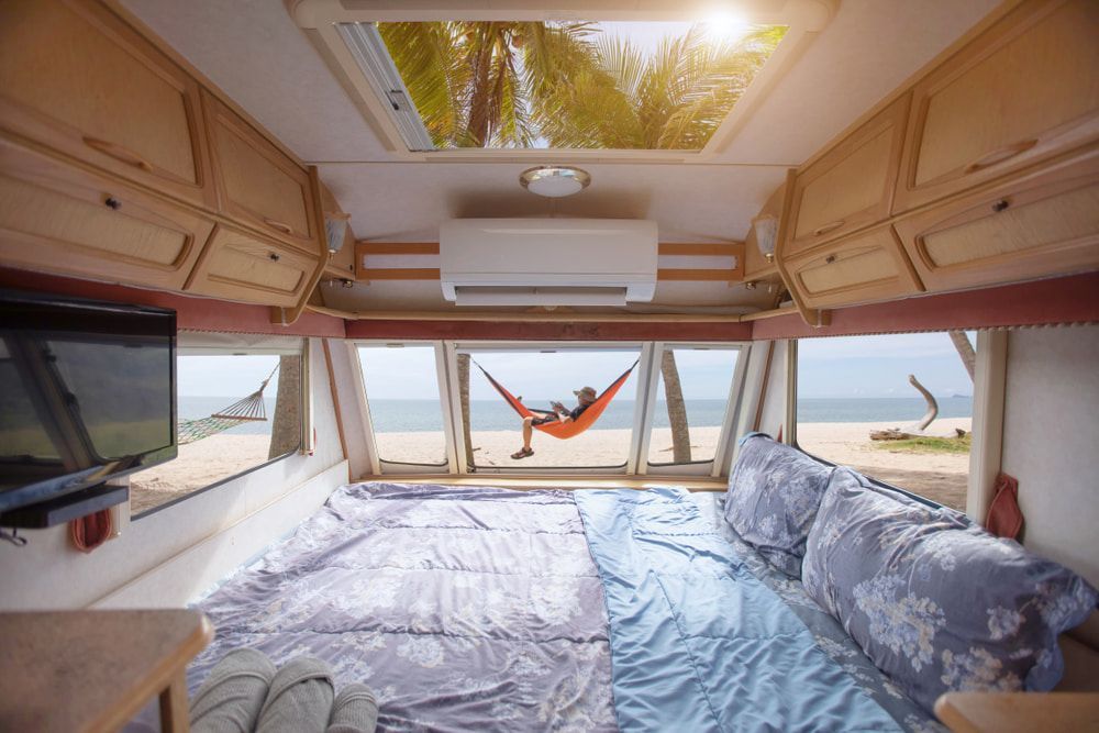 Caravan Bedroom With Air Conditioner And Man Laying In Hammock — Caravan Air Conditioner in Kempsey, NSW