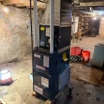 Close-up of a furnace component with wires, a gas valve, and spark plugs, likely for maintenance.