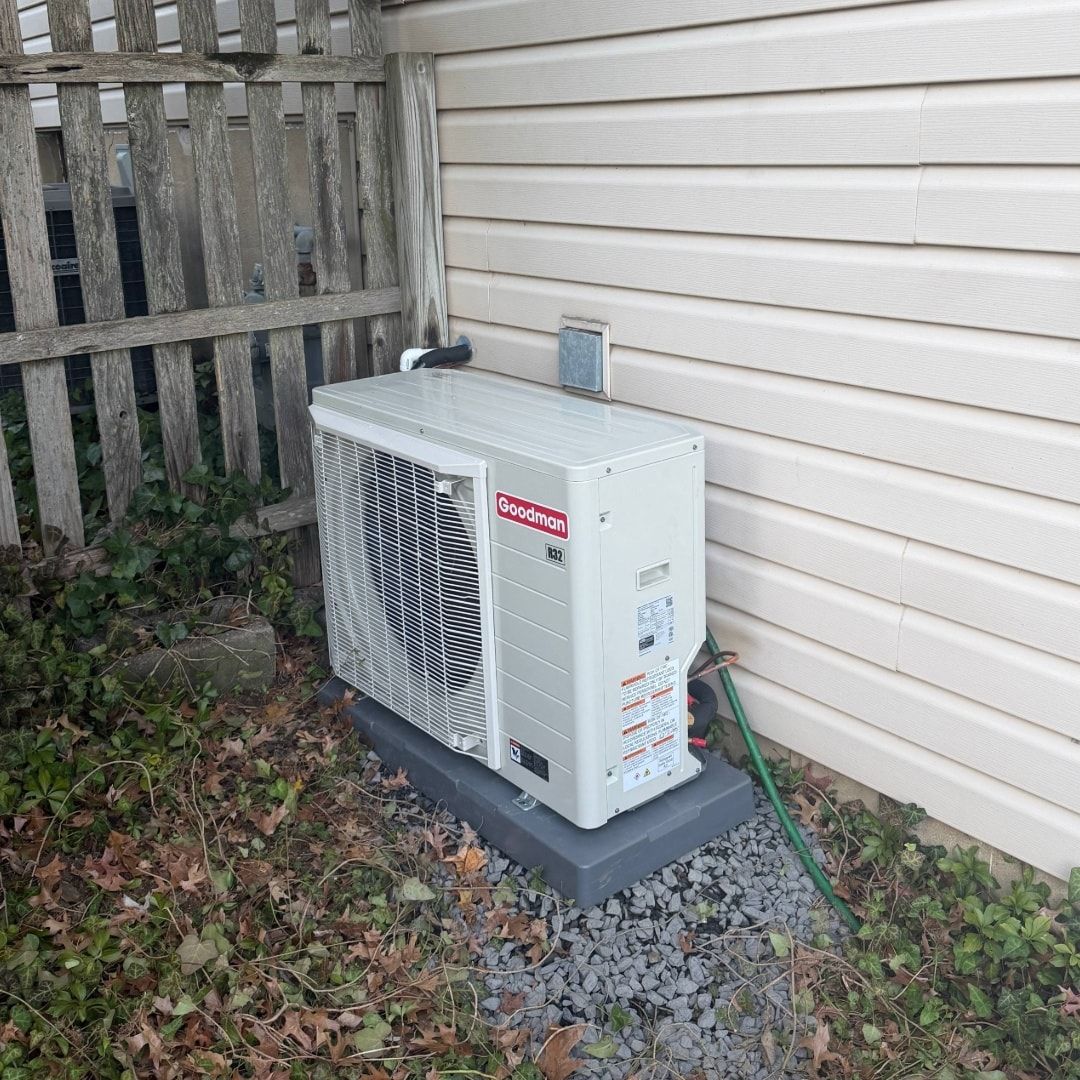 Two rusty air conditioning units sitting on concrete pads next to a building.