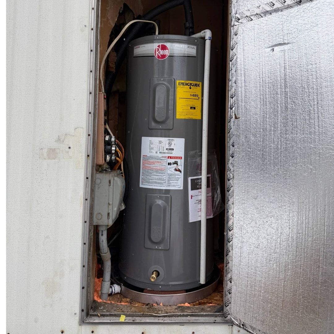 Leaking water heater in a basement. Water on concrete floor, gas valve visible.