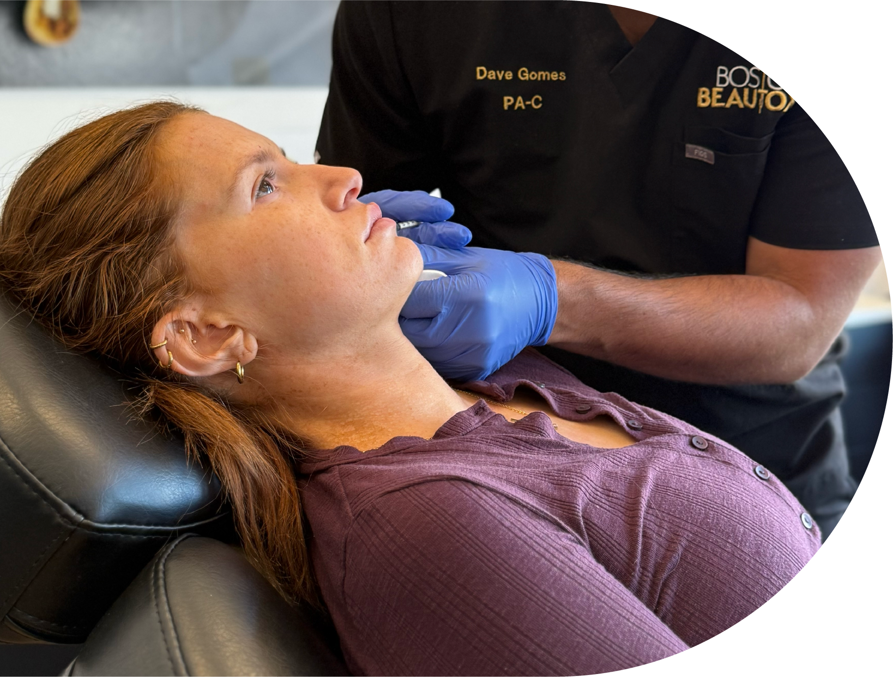 Person receiving facial injections from a healthcare provider wearing black gloves; in a medical setting.