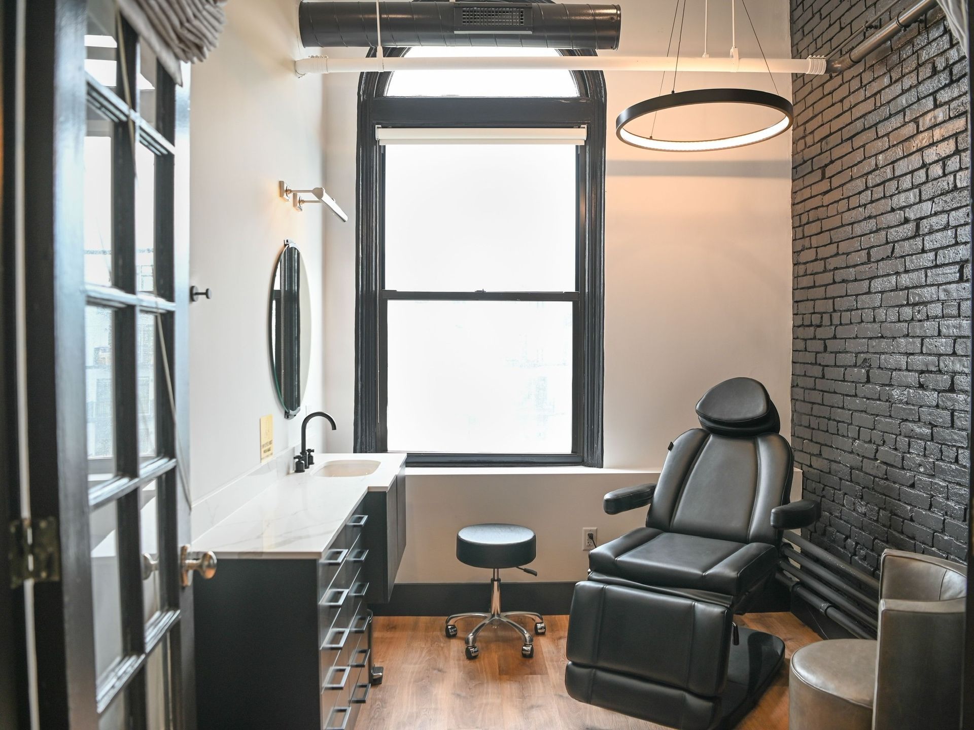 Treatment room in South Boston-with chair, sink, window, and black brick wall.