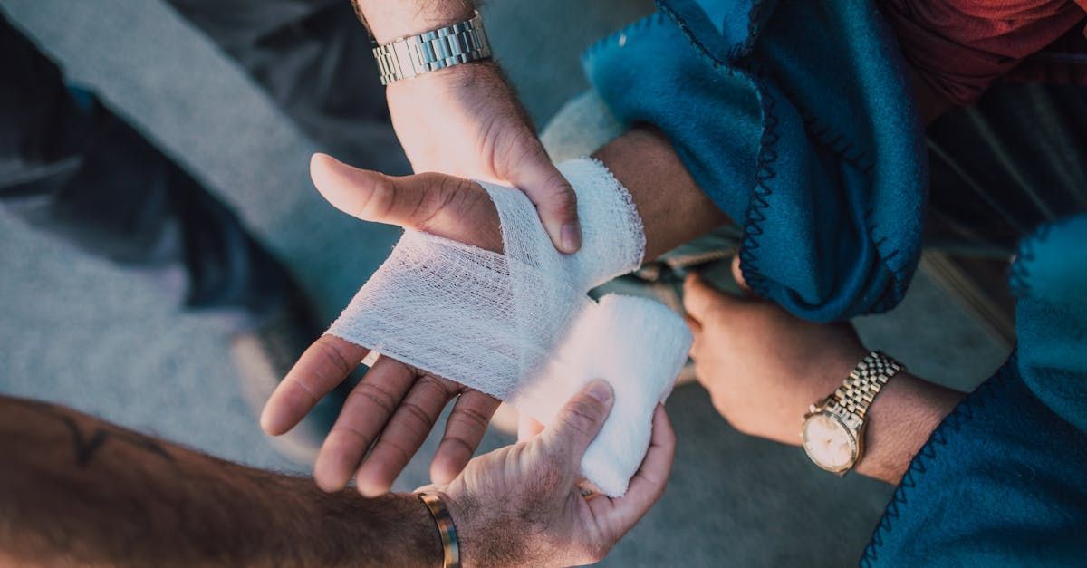 A person is wrapping another person 's hand with a bandage.