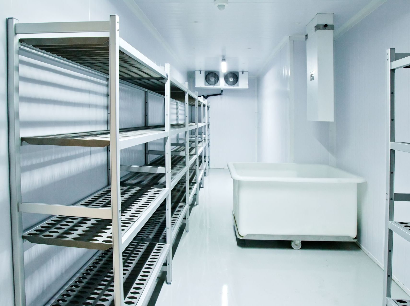 A room with stainless steel shelves and a white container