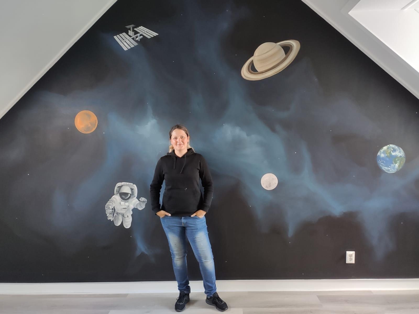 muurschildering met Asiya ervoor ruimtevaart heelal thema donker blauw zwarte achtergrond