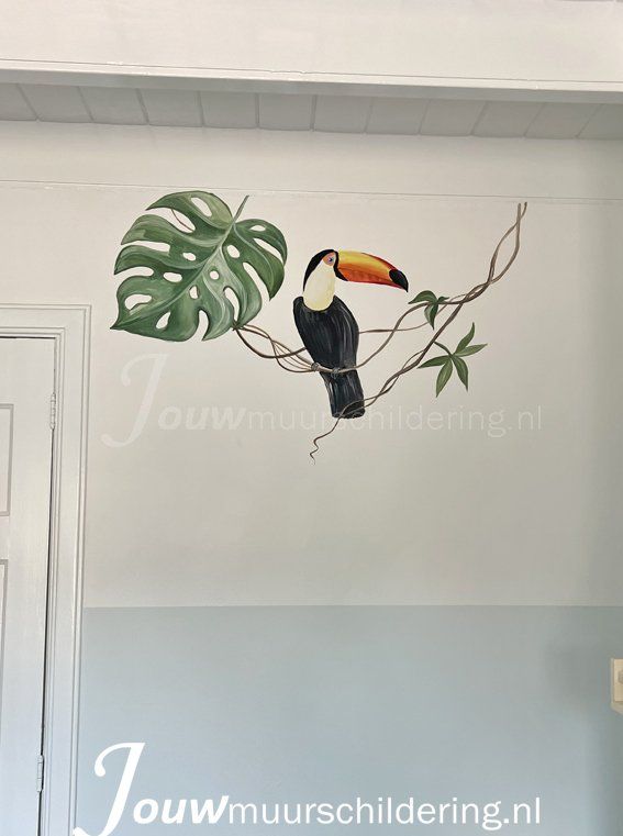 muurschildering ingezoomd op toekan op groen blad witte muur
