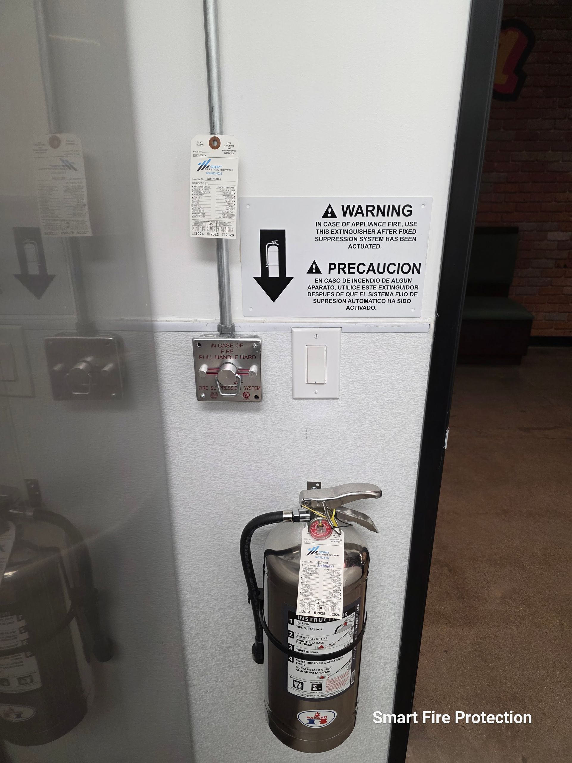 Fire extinguisher mounted on wall next to electrical fixtures with warning sign.