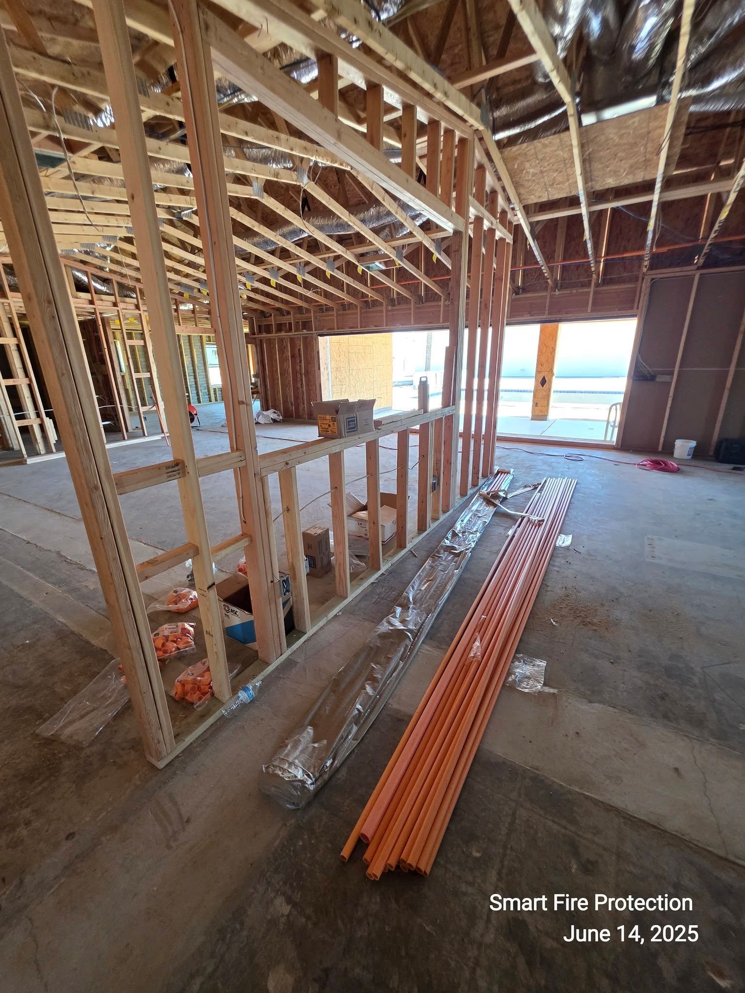 Interior view of a building under construction, showing wooden framing, orange conduit, and open space.