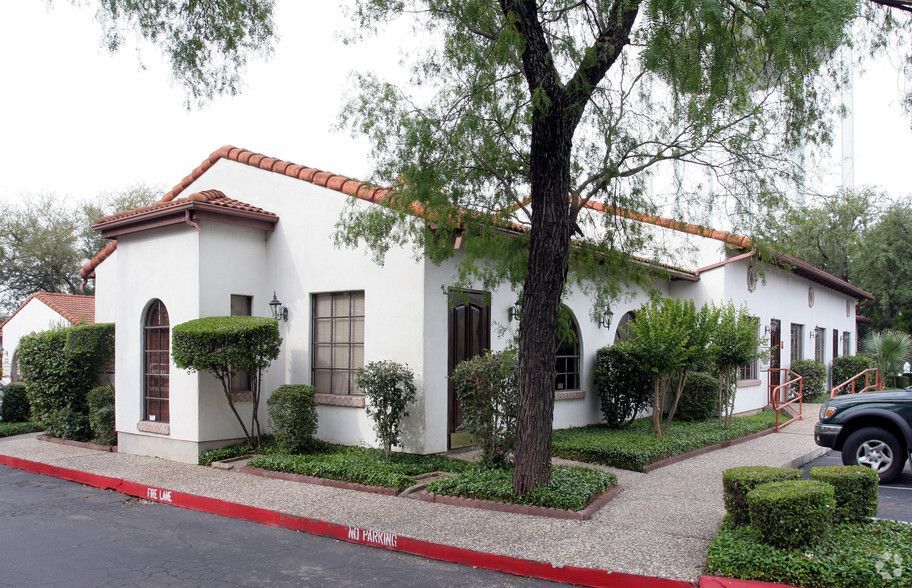A white building with a red roof and a tree in front of it