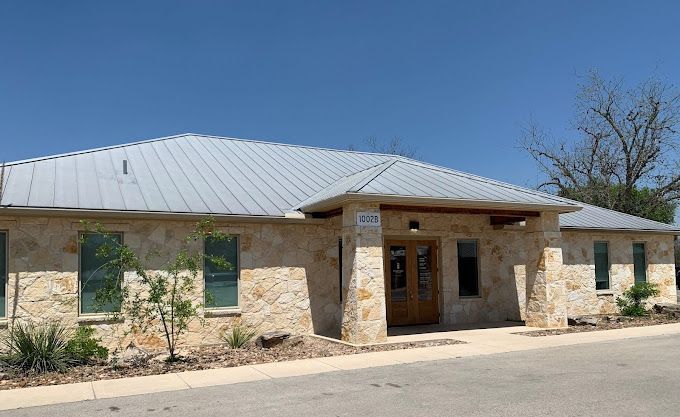 A large stone building with a metal roof and a lot of windows.