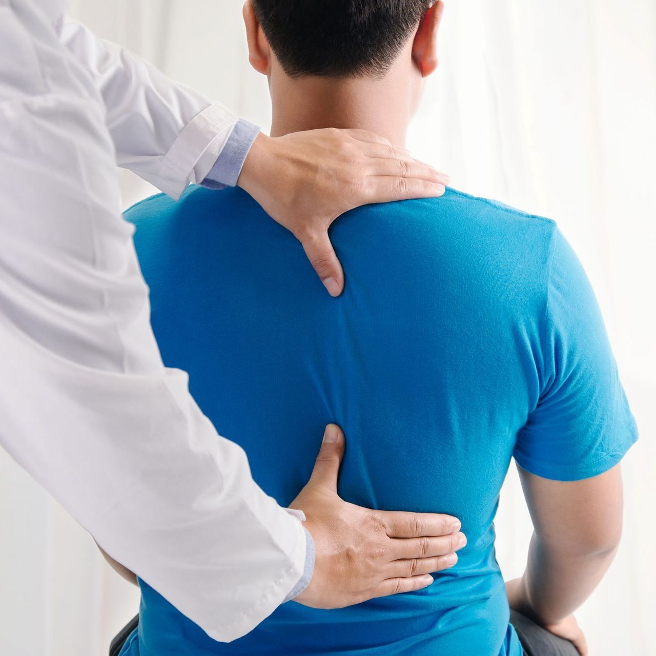 Doctor physiotherapist doing healing treatment on man's back.Back pain patient, treatment, medical doctor, massage therapist.office syndrome.