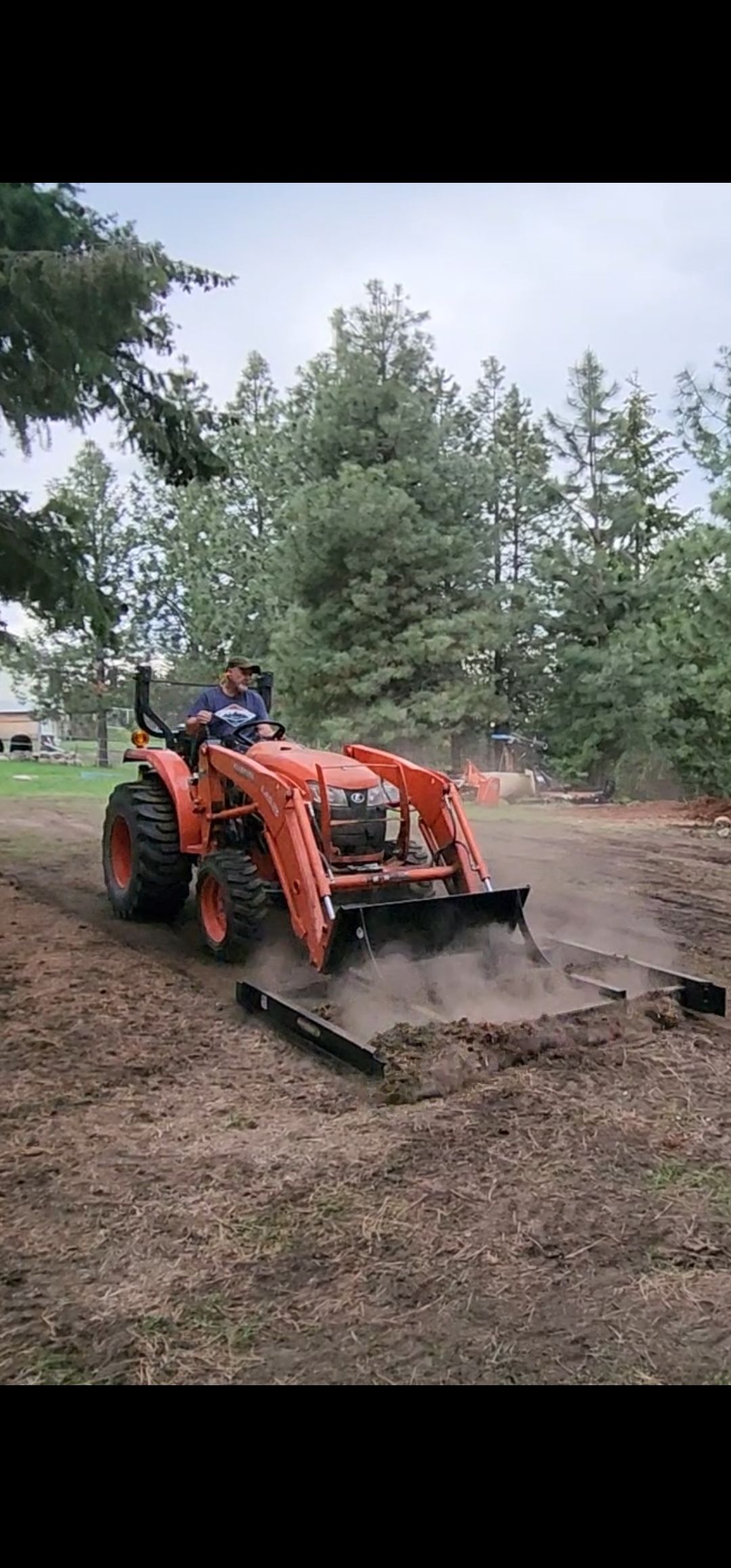 A man is driving a tractor on a dirt road.