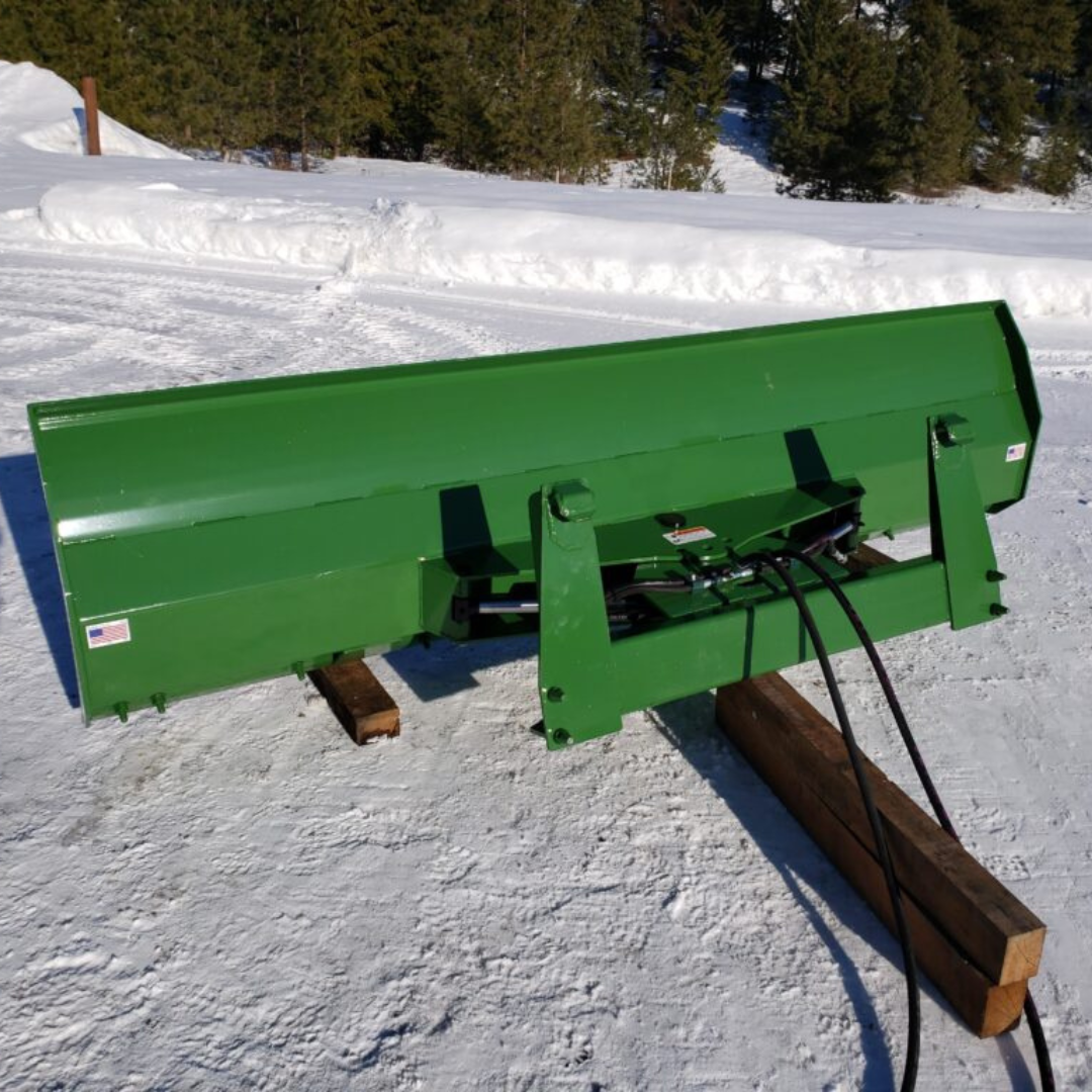 A green snow plow is sitting in the snow