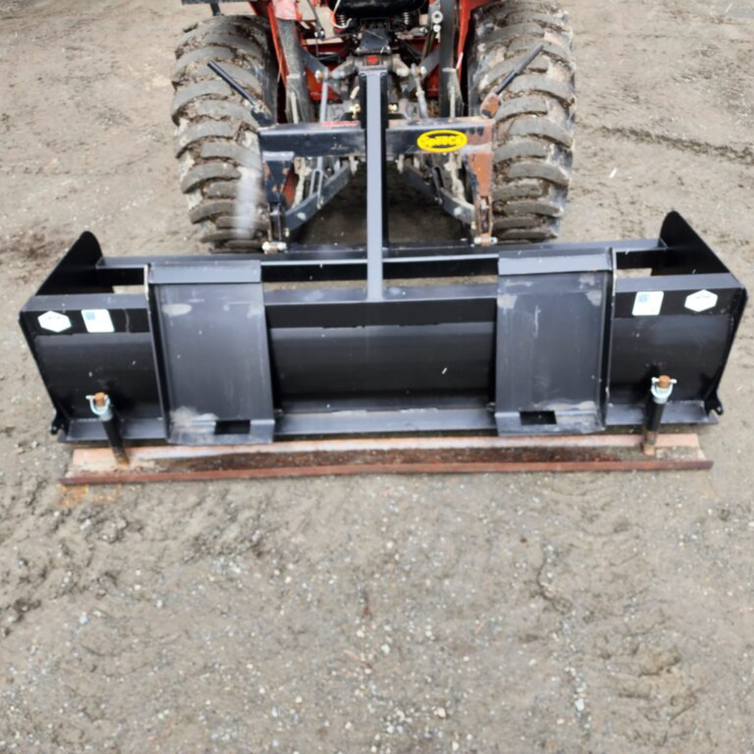 A tractor is parked on a dirt road with a black bucket attached to it