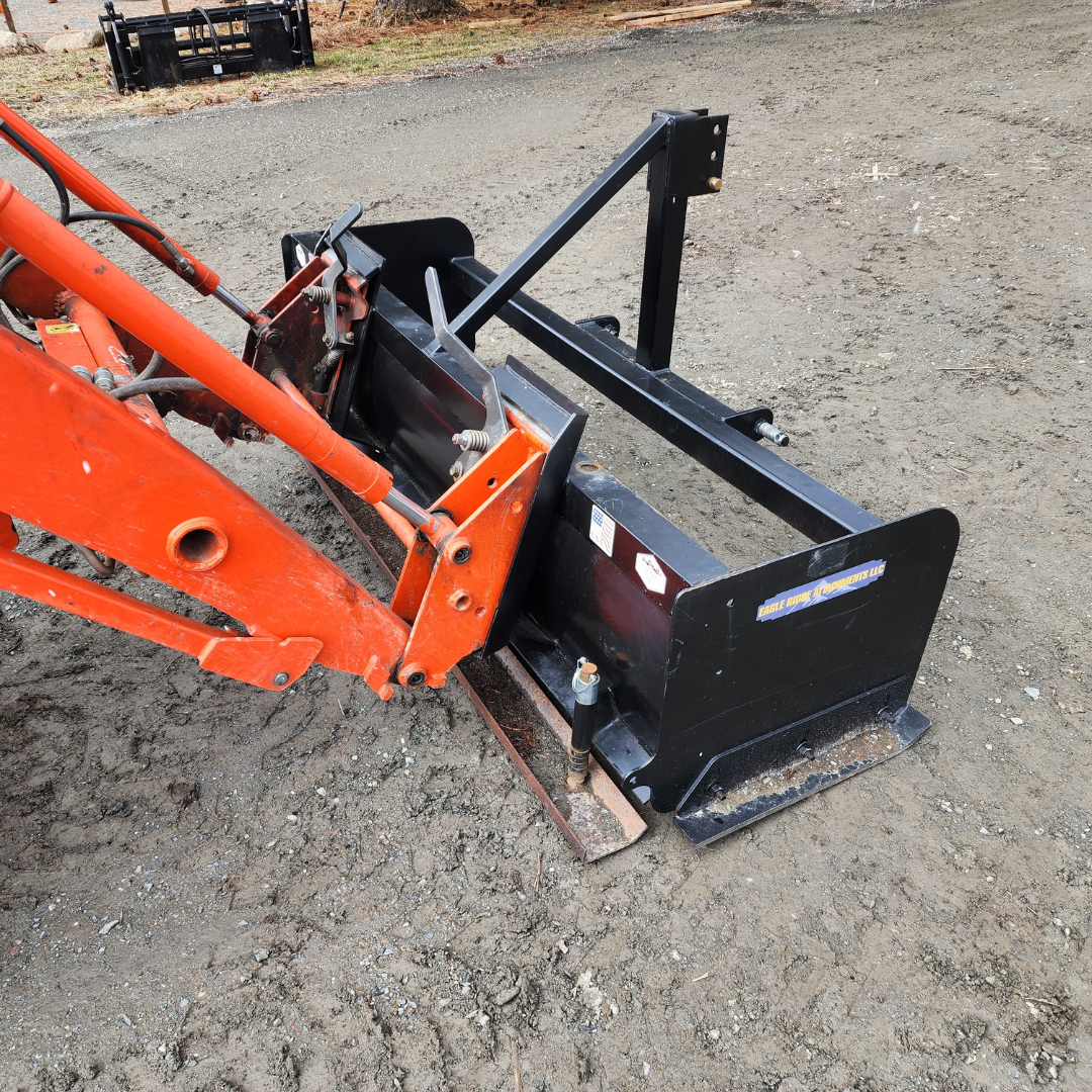 An orange tractor with a black bucket on the ground