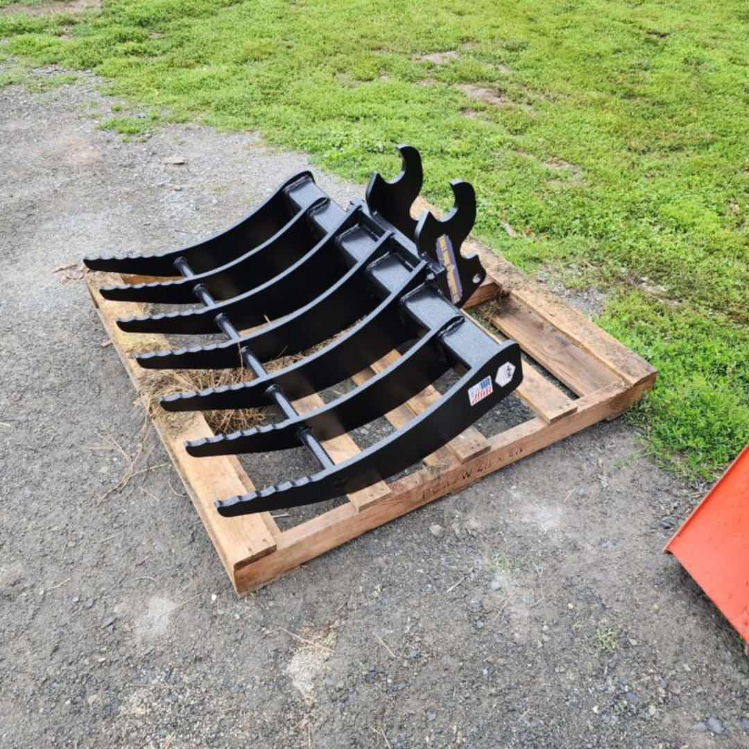 A black rake is sitting on top of a wooden pallet.