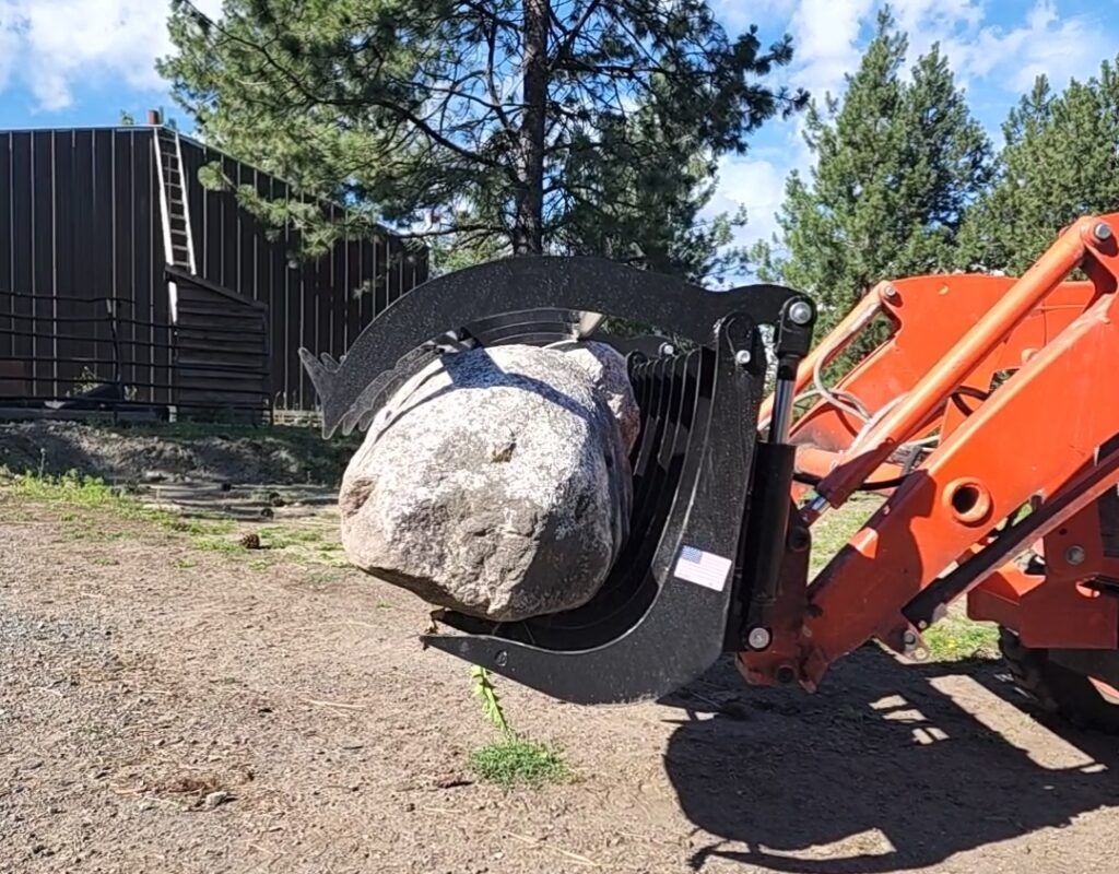 A large rock is being lifted by a tractor