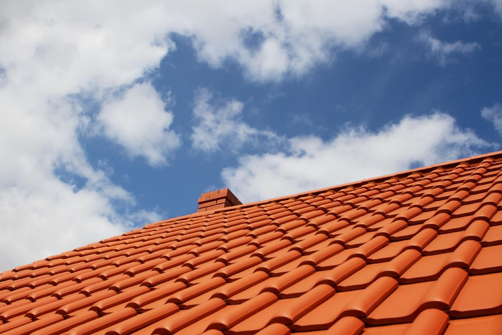 Red Tiled Roof With Chimney Under Blue Sky