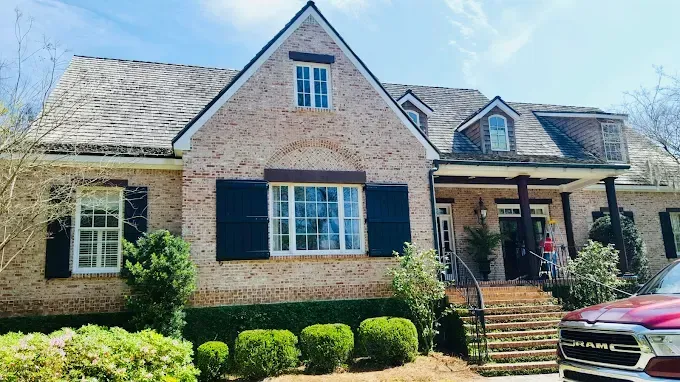 White stucco house with dark window frames; SUV parked in circular drive; green lawn and flowerbeds.