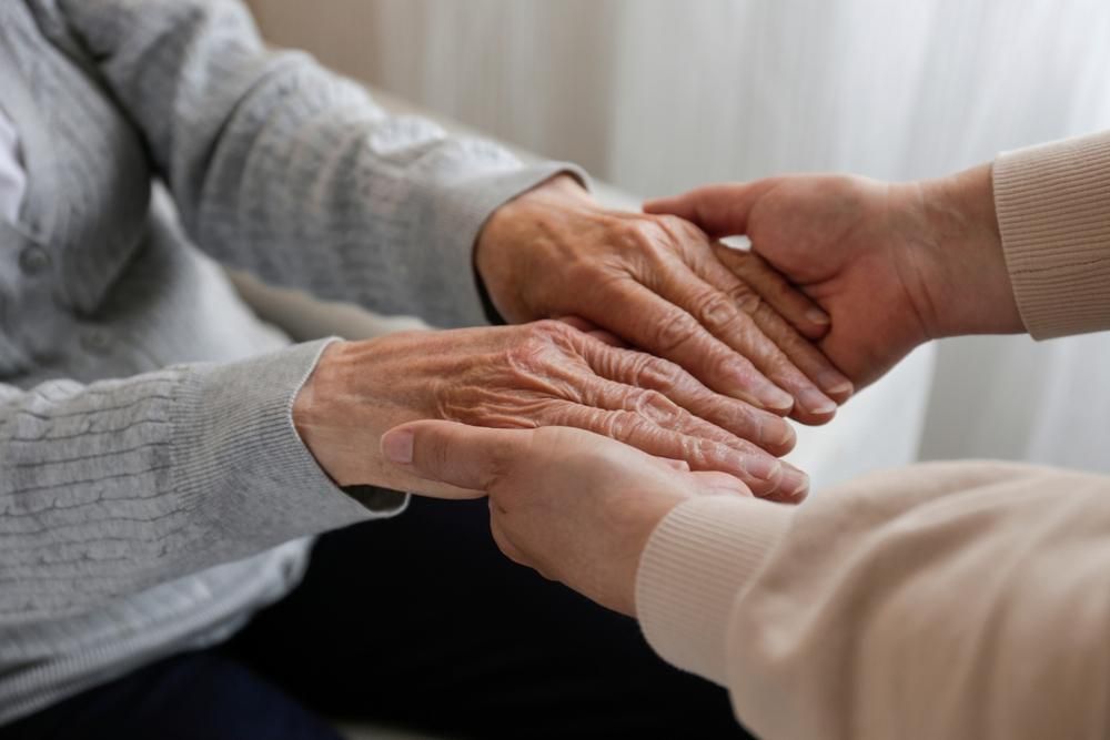 Two people holding hands, one with wrinkled hands, close-up.