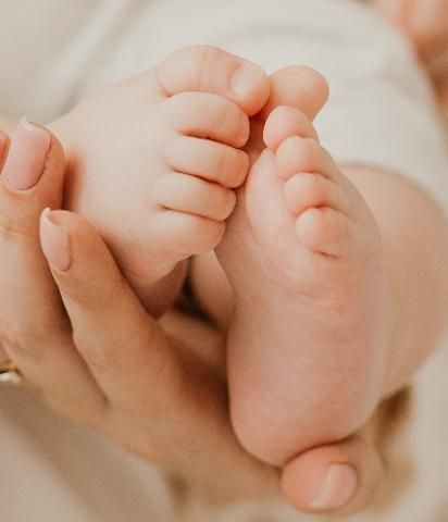 A pair of baby feet held gently in a person's hands.