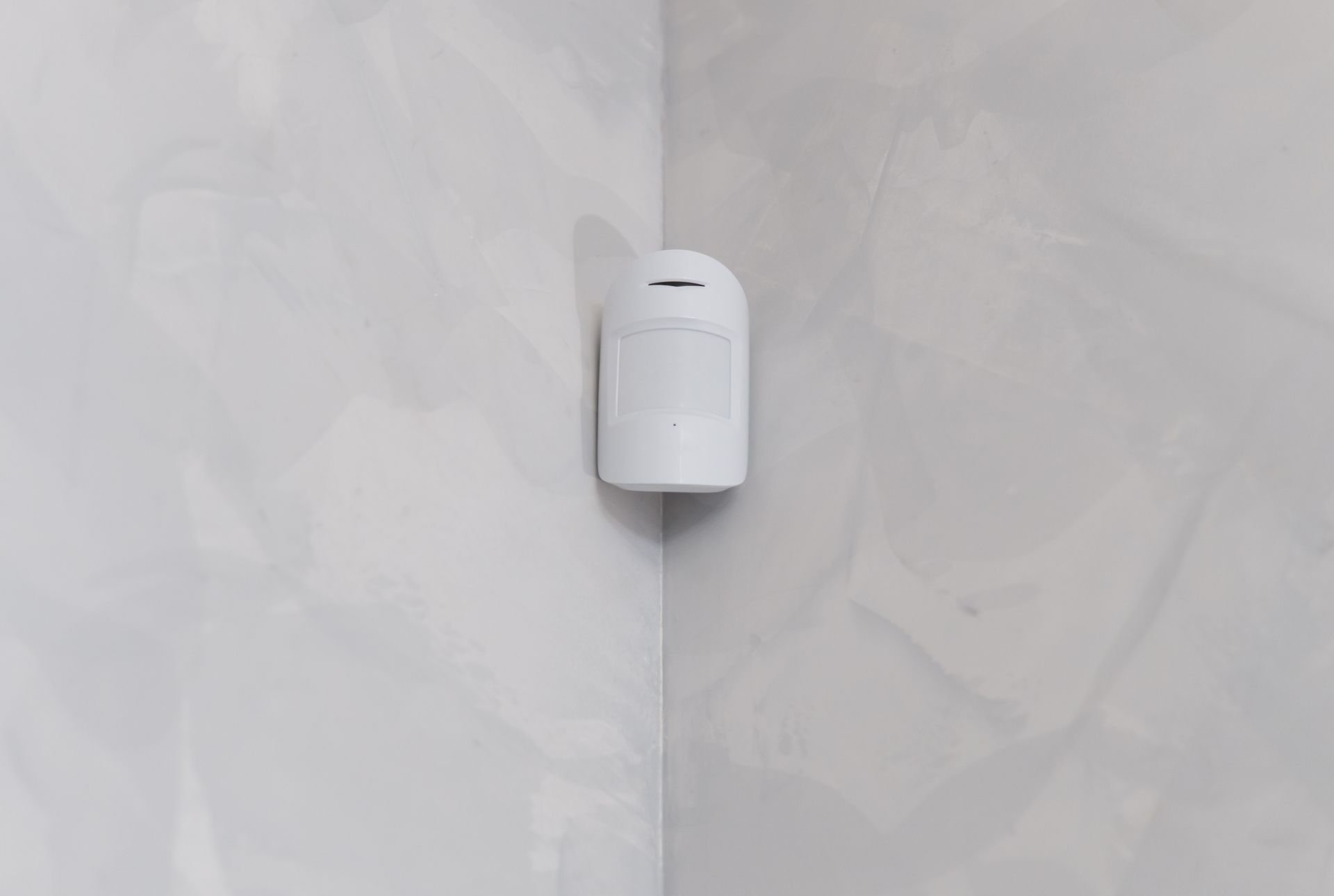 Un sensor de movimiento blanco está montado en la esquina de una pared.