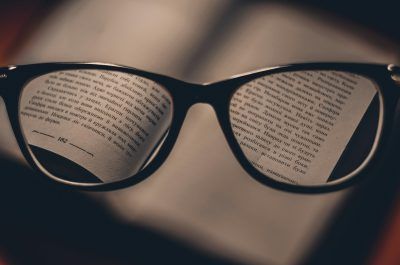 Glasses reflecting pages of an open book.