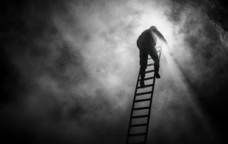 Person climbing a ladder towards bright light in a dark, smoky environment.