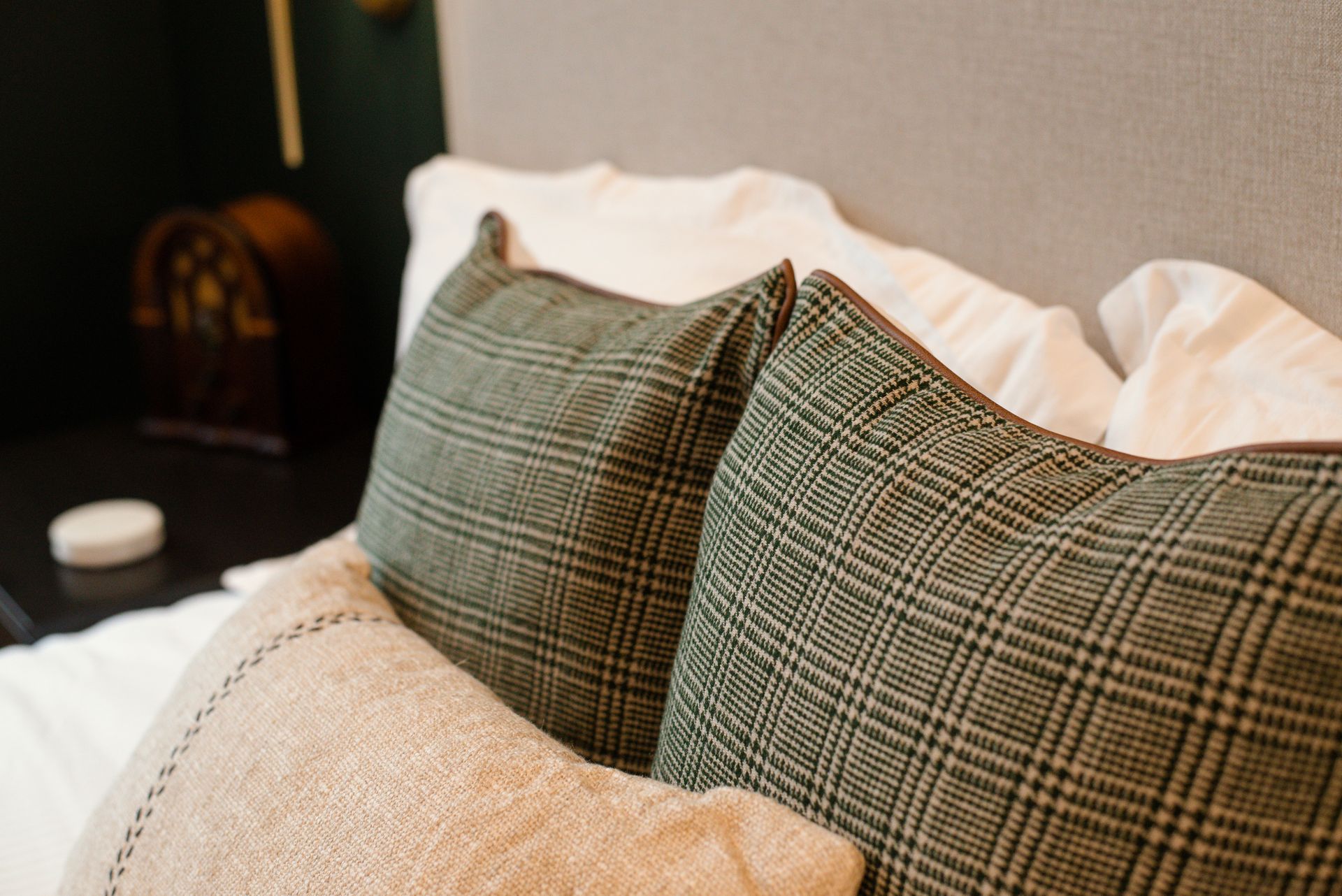 Close-up of a bed with green plaid and tan throw pillows.