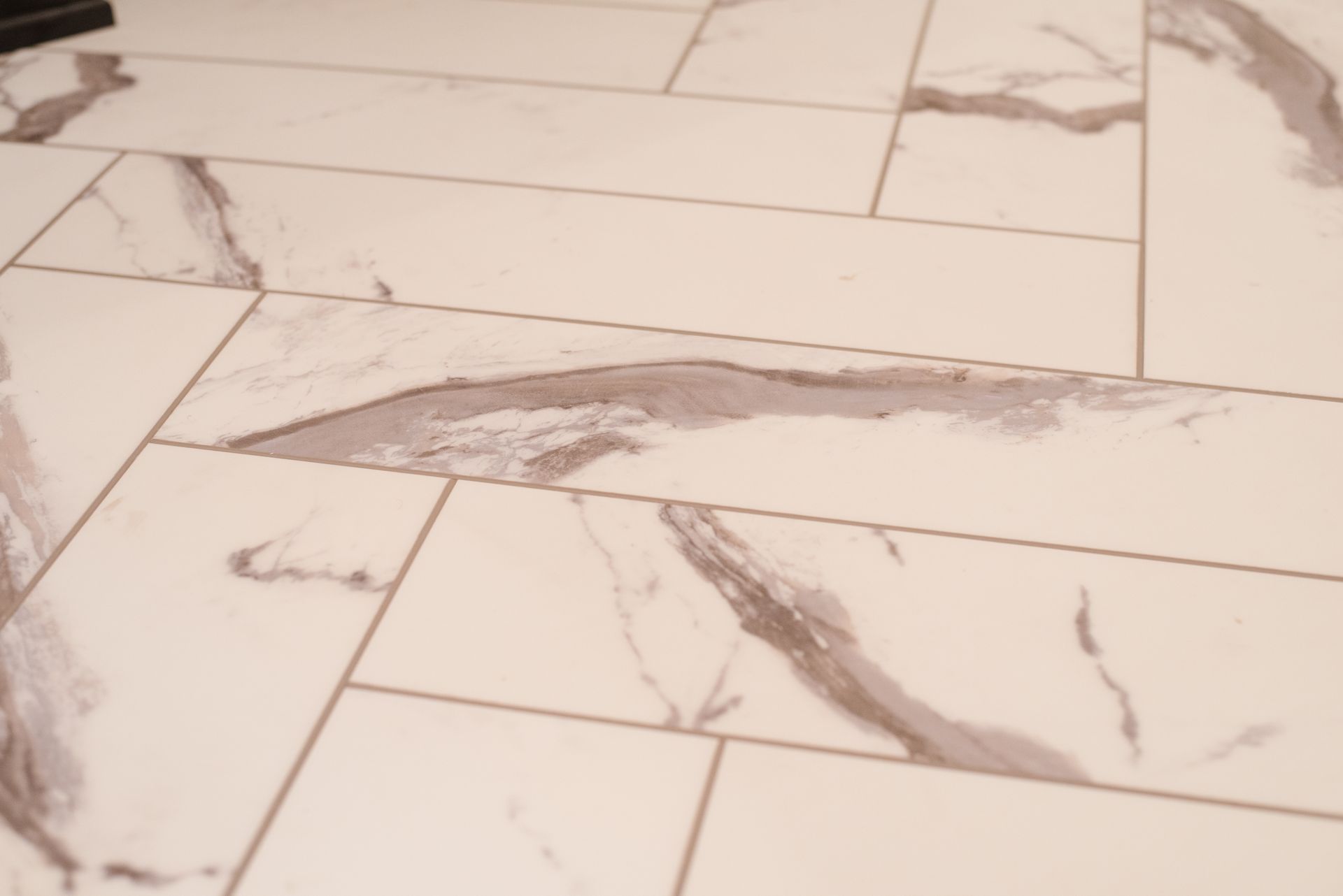 Herringbone pattern tile floor with white and gray veining.