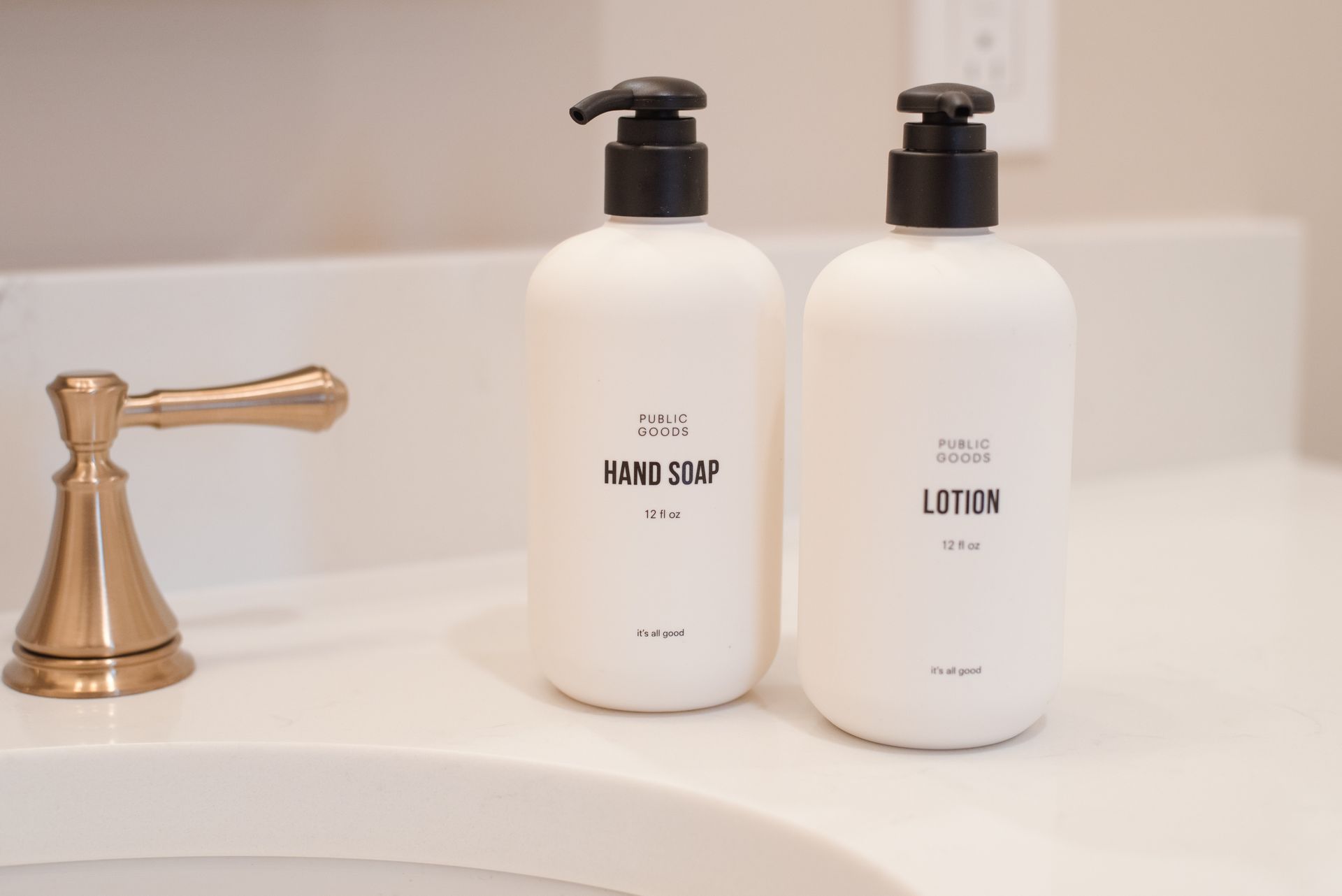 White hand soap and lotion dispensers with black pumps on a bathroom counter.